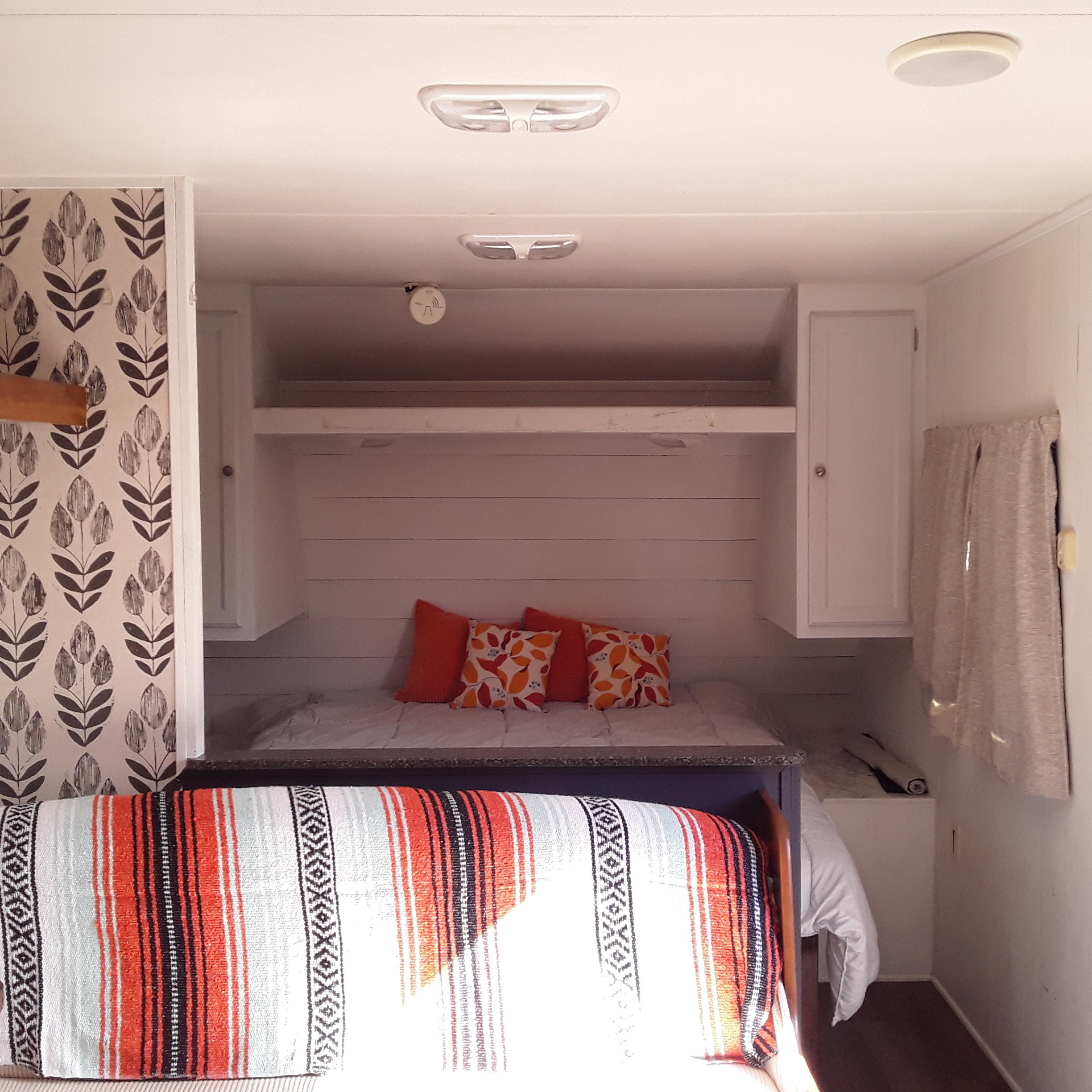 Step inside this cozy RV rental's bedroom, featuring a vibrant bed with colorful pillows & patterned wallpaper.. Heartland RVs Trail Runner 2013