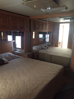 RV rental bedroom with a comfortable bed, wood cabinetry, and mirrored closet doors reflecting the interior.. Four winds Mandalay 40E 2005