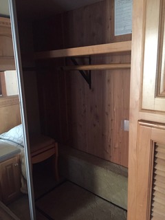 Spacious wooden wardrobe inside an RV rental, featuring a shelf and hanging rod for clothing storage.. Four winds Mandalay 40E 2005