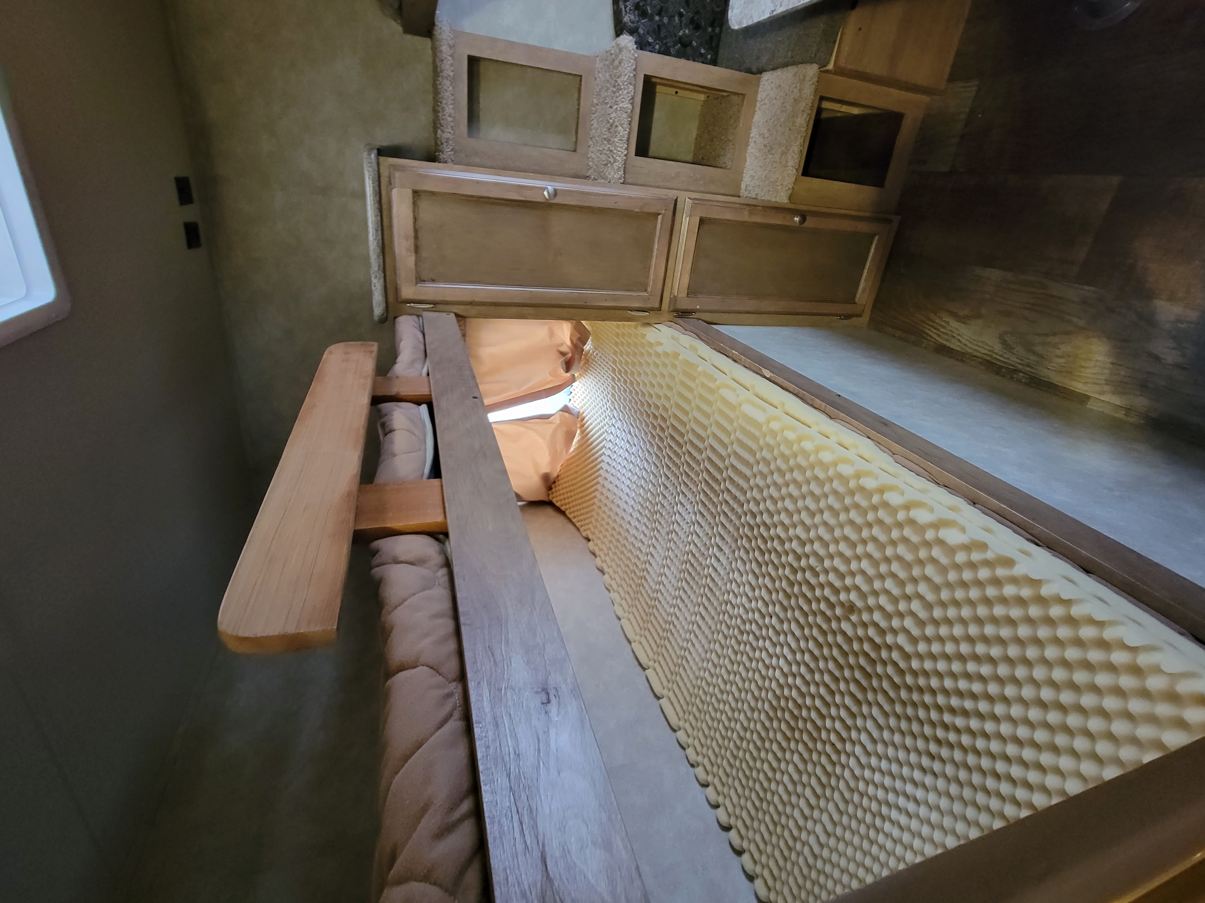 RV rental bedroom with egg-crate mattress topper, wooden slat bed frame, and overhead storage.. Gulf Stream Gulf Breeze Ultra Lite 2016