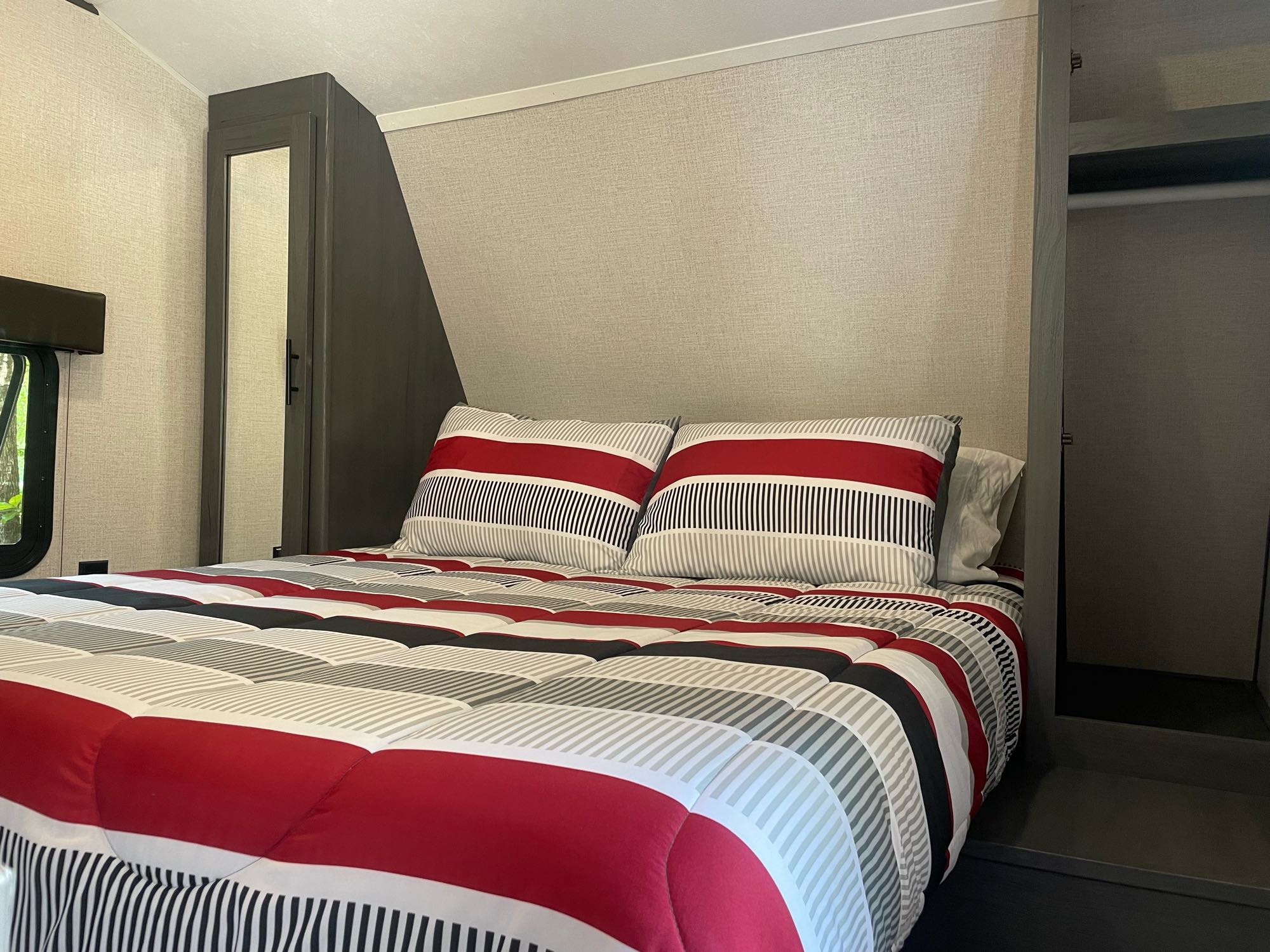 RV rental bedroom: Cozy bed with striped bedding, mirrored closet. Perfect for your travel and vacation comfort.. Aspen Trail 25 BH 2022