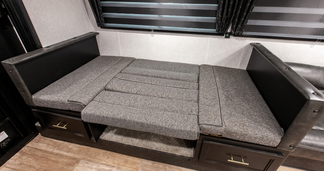 RV rental's gray convertible dinette/sofa bed, featuring storage drawers.. Forest River Cherokee Grey Wolf 2022