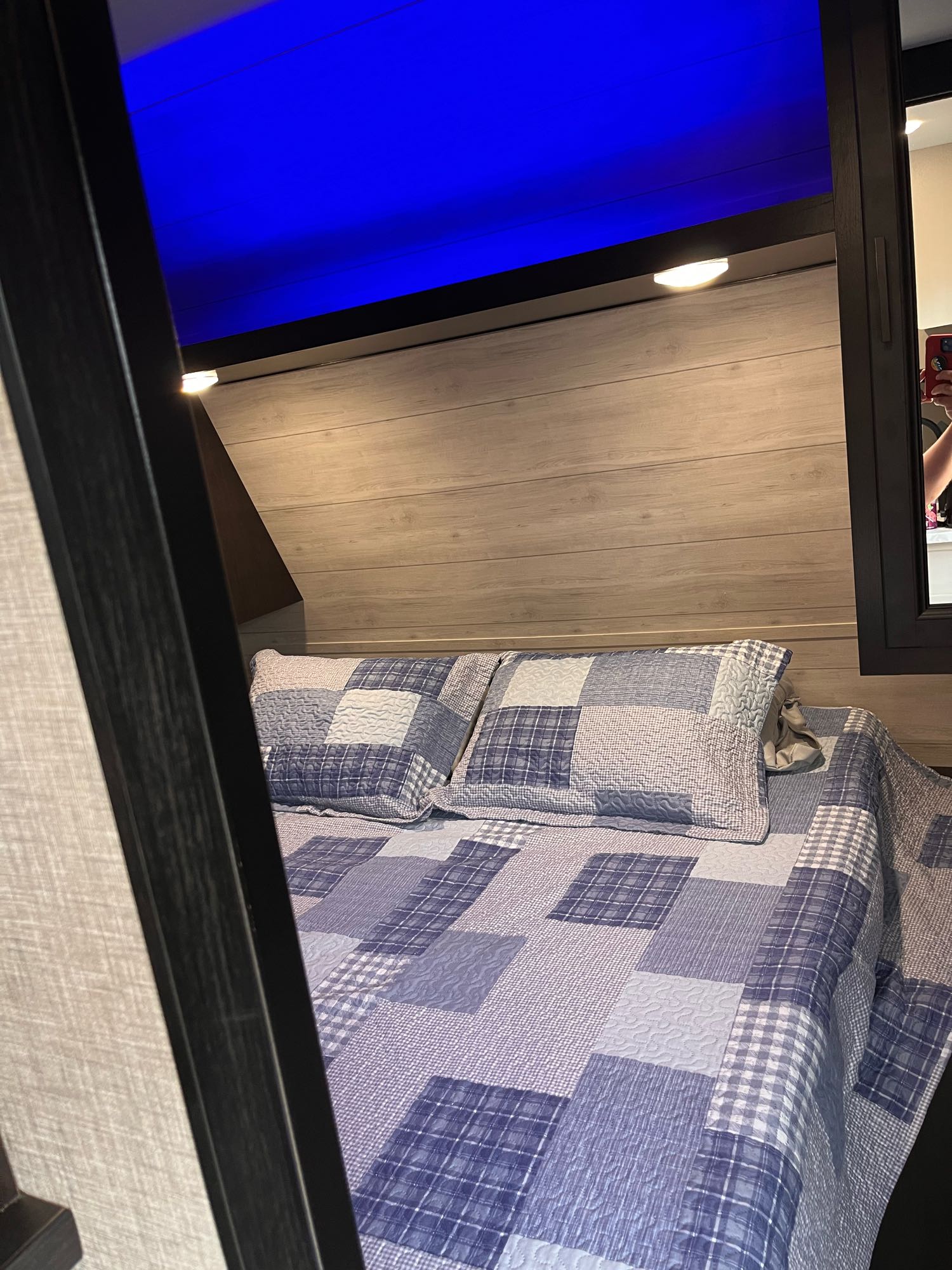 RV rental bedroom showing a patchwork quilt bed, wood headboard, and vibrant blue overhead lighting.. Jayco Jay Flight 2022