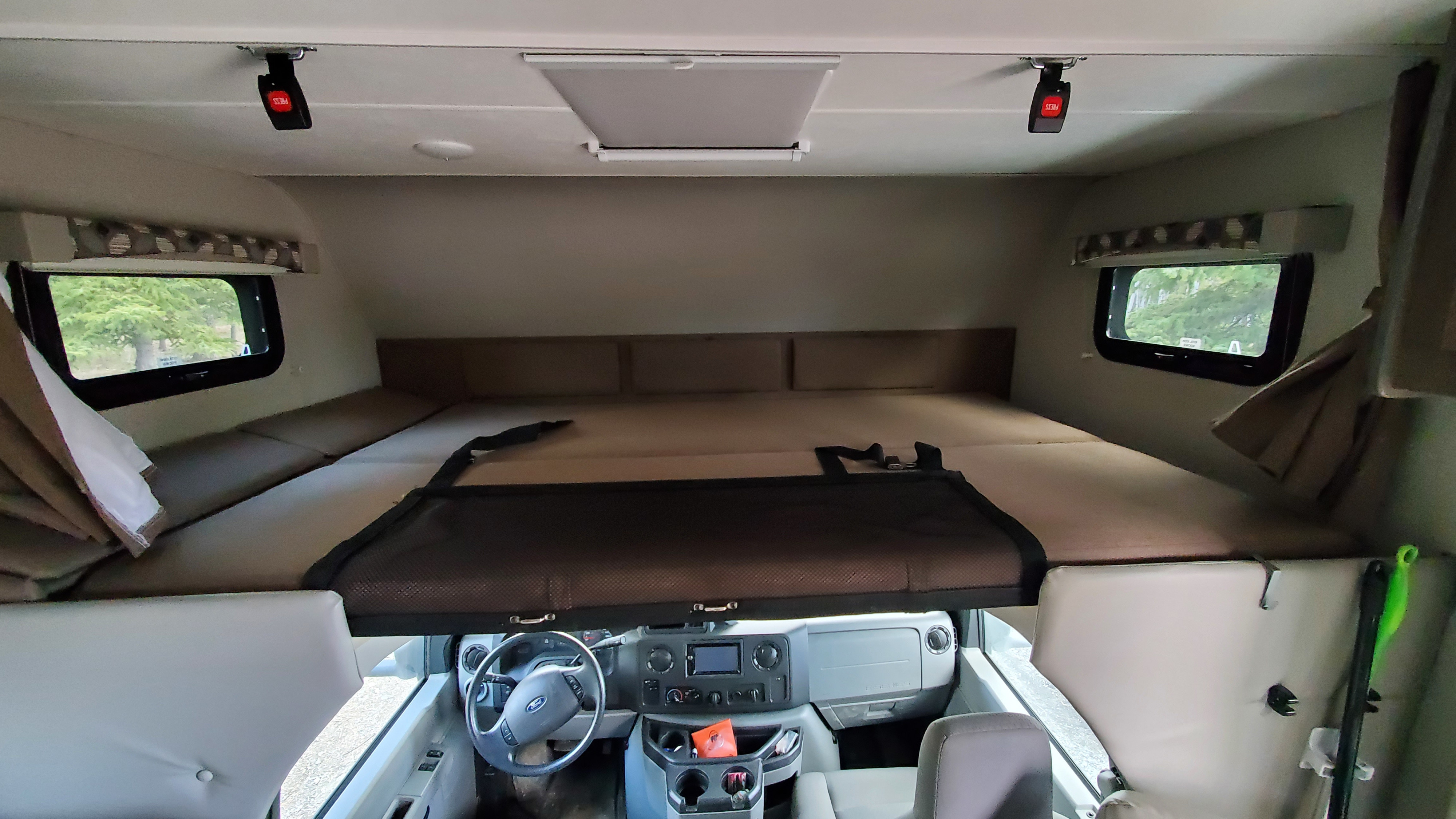 Interior of an RV rental, featuring the driver's cockpit below a spacious cab-over bunk bed with a safety net.. Adventurer Adventurer Motorhome 2019