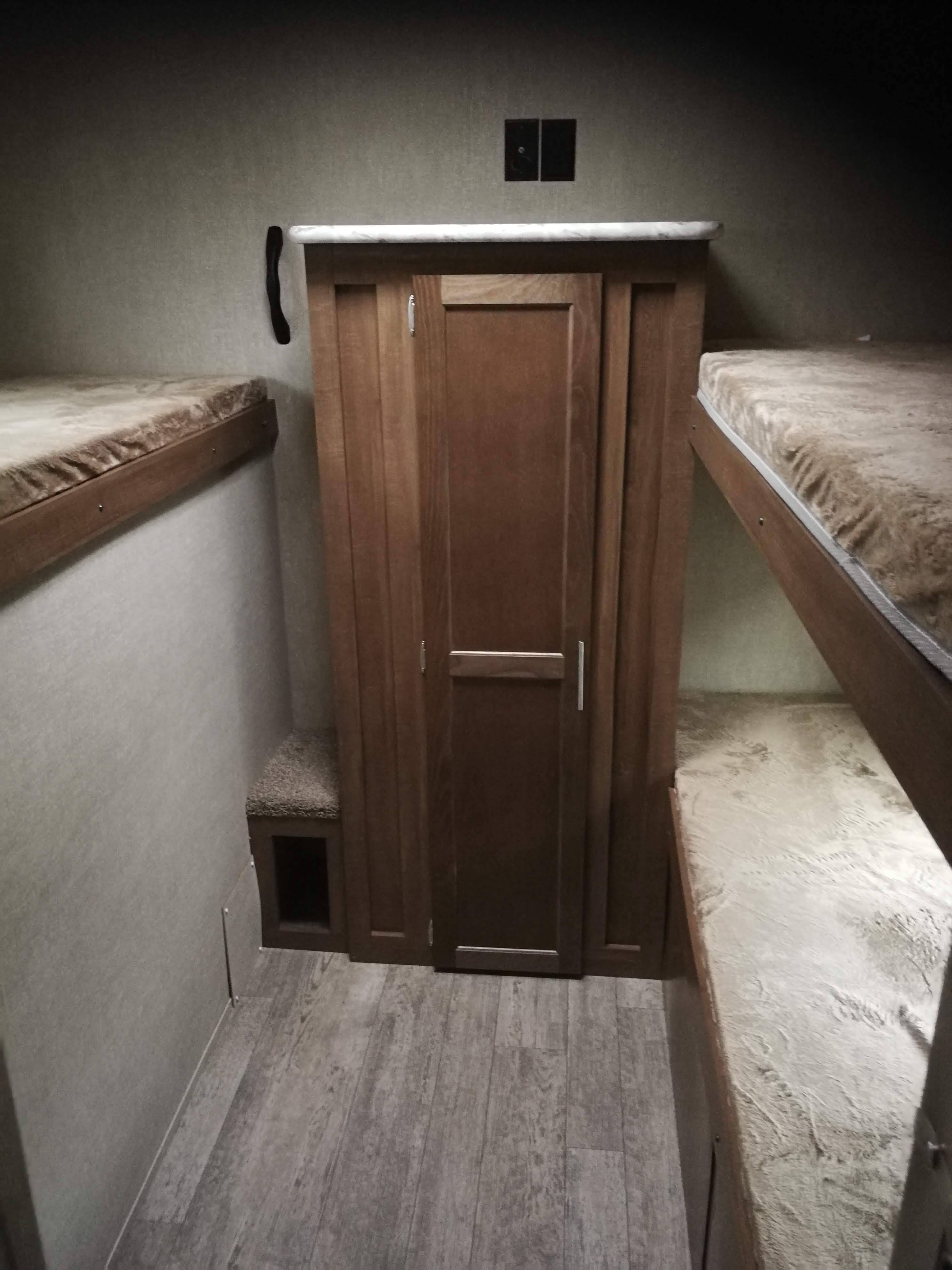 An RV rental bunkhouse features multiple bunk beds on both sides and a central storage unit.. Grand river 32bhs 2019