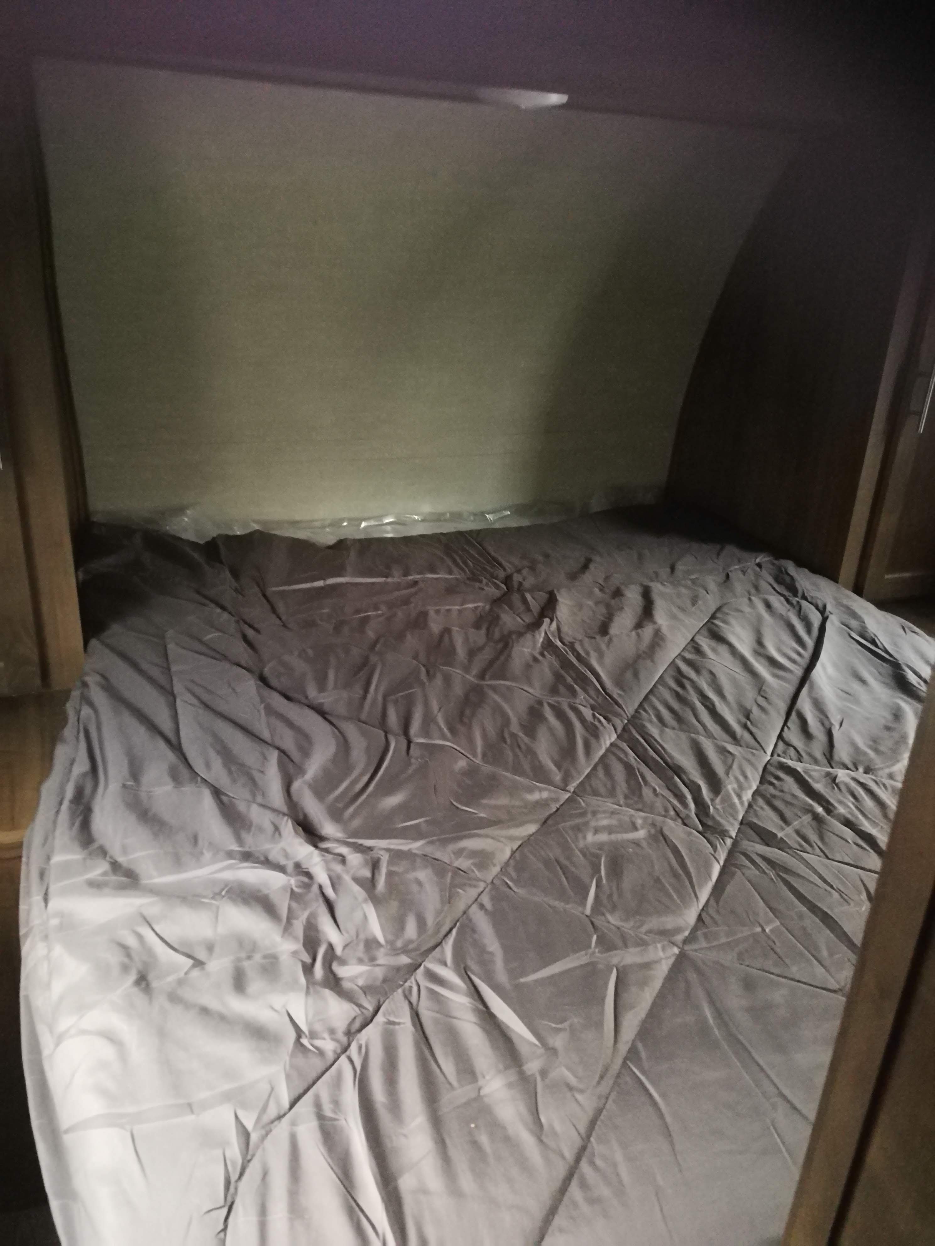 RV rental bedroom featuring a bed with a grey comforter and plastic-wrapped mattress in a compact space.. Grand river 32bhs 2019