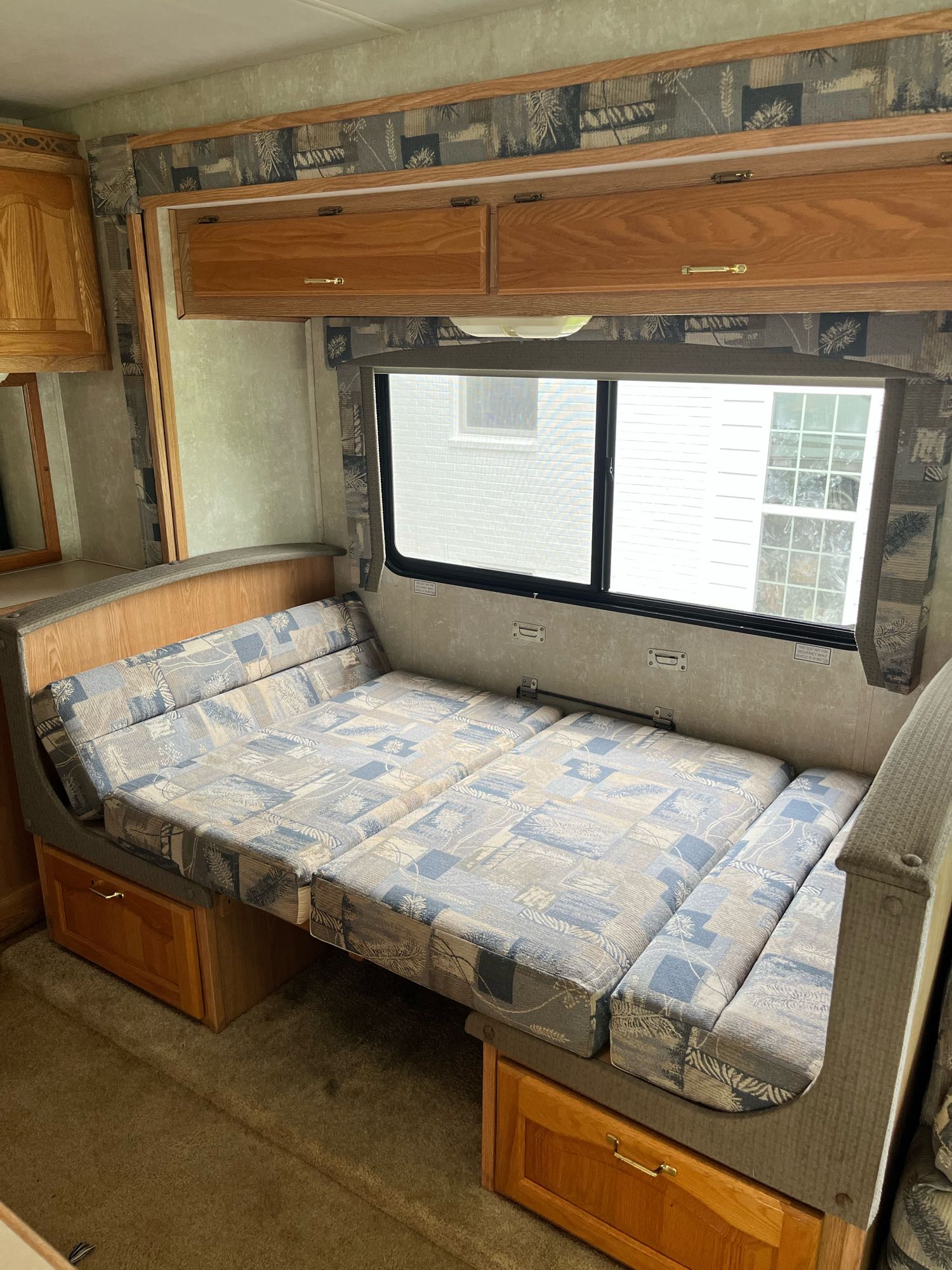 RV rental interior features a convertible dinette bed, overhead cabinets, and window view.. Forest River Georgetown 2002