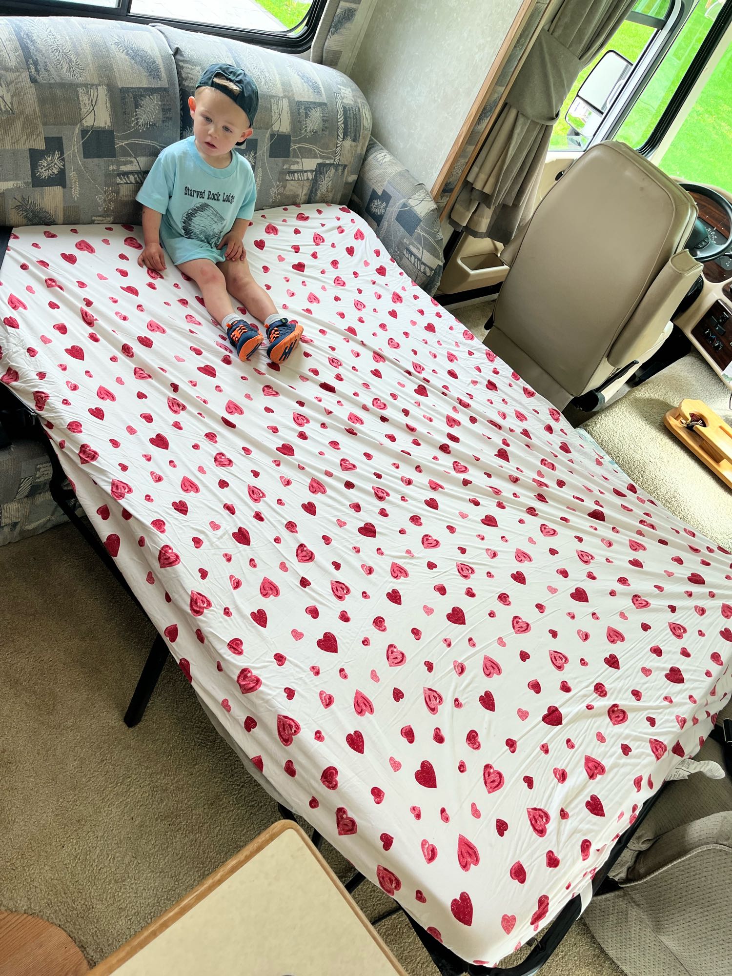 Young child on a heart-patterned bed inside an RV rental, a comfy spot for family adventures.. Forest River Georgetown 2002