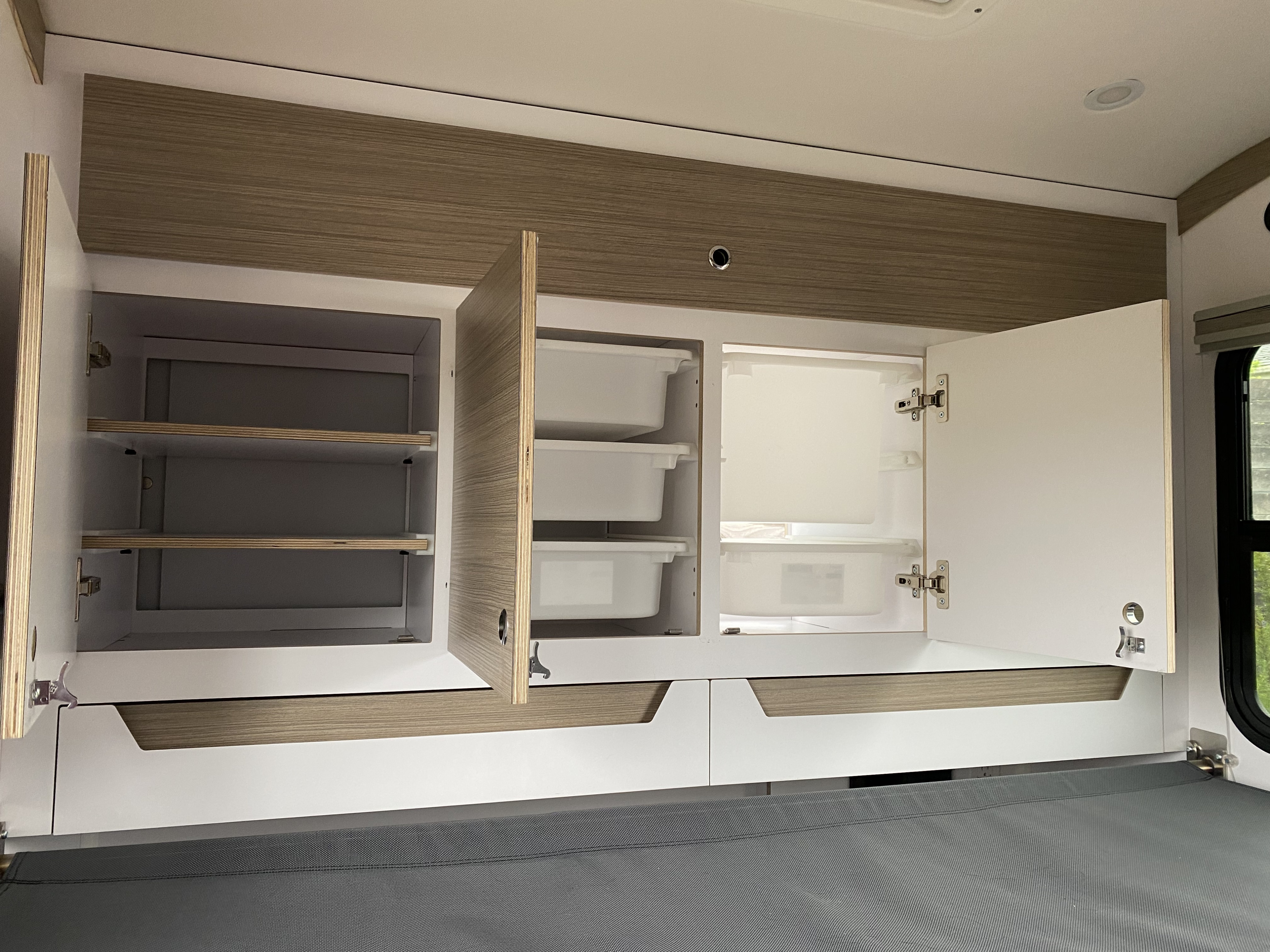 RV rental: Overhead cabinets open revealing ample storage with adjustable shelves & pull-out bins in a camper.. Bean Teardrop Trailer 2022