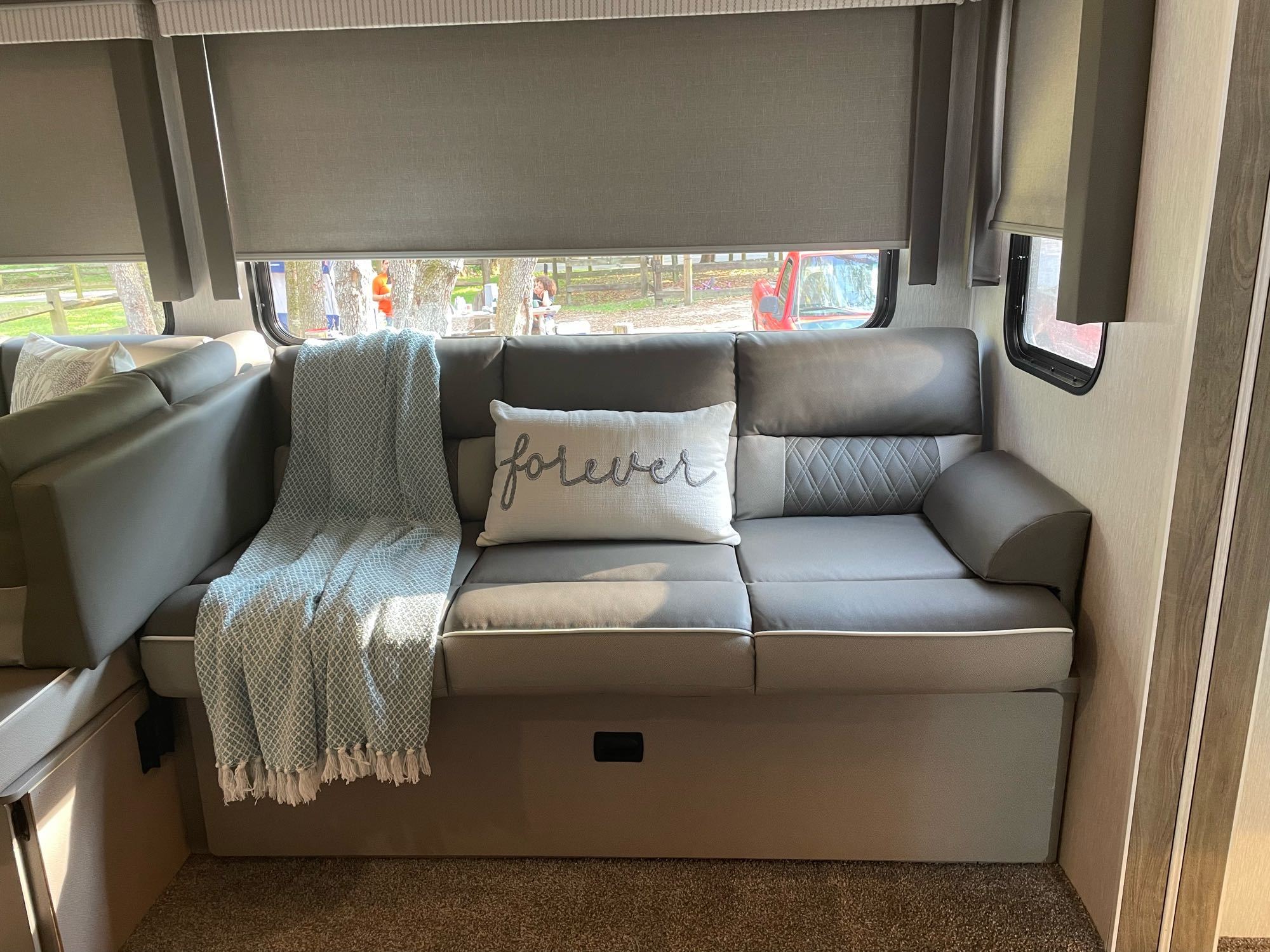 RV rental interior featuring a cozy gray sofa, "forever" pillow, & blue blanket, perfect for relaxing after a road trip.. Forest River Salem 2022
