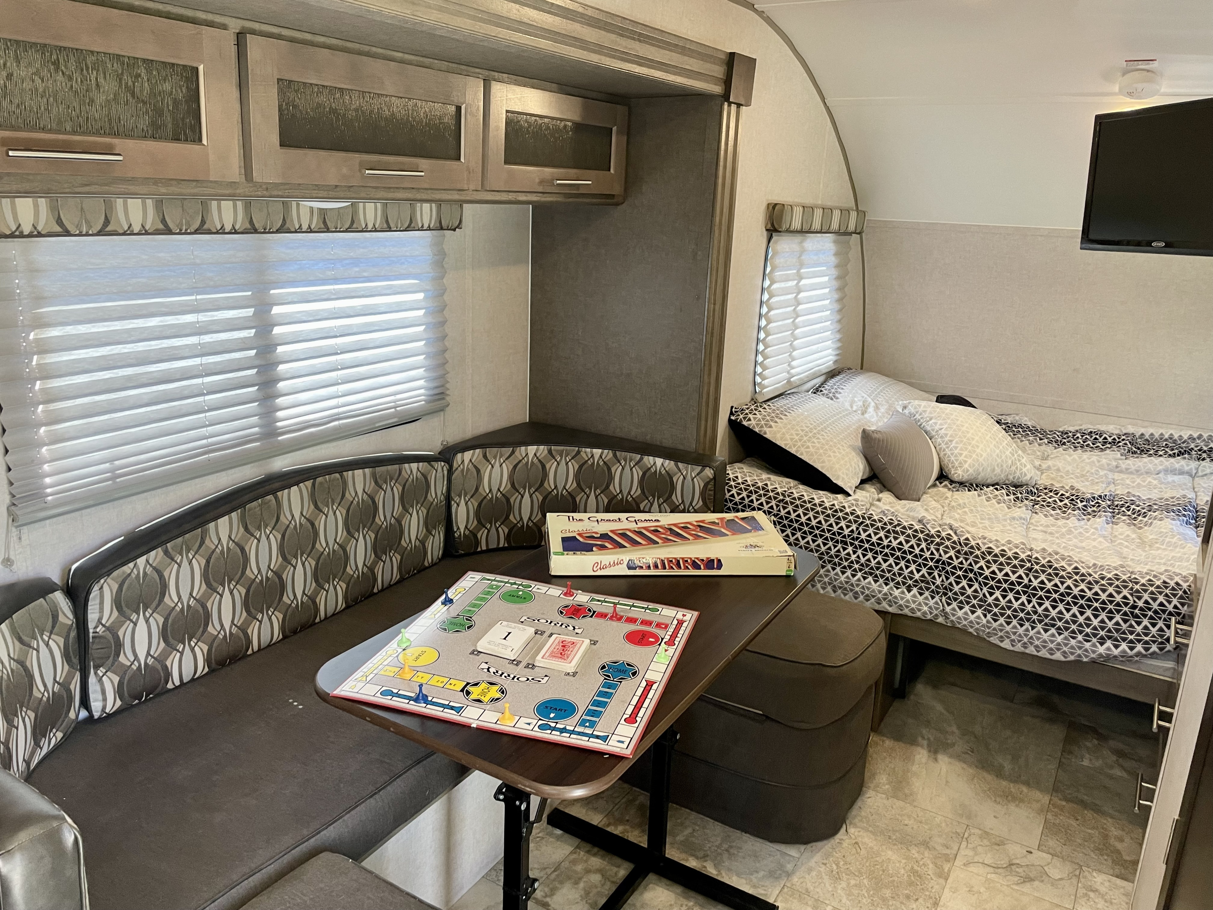 This RV rental features a compact living space with a comfortable bed, a dinette, and a Sorry! board game setup.. R-Pod Hood River Edition 2017
