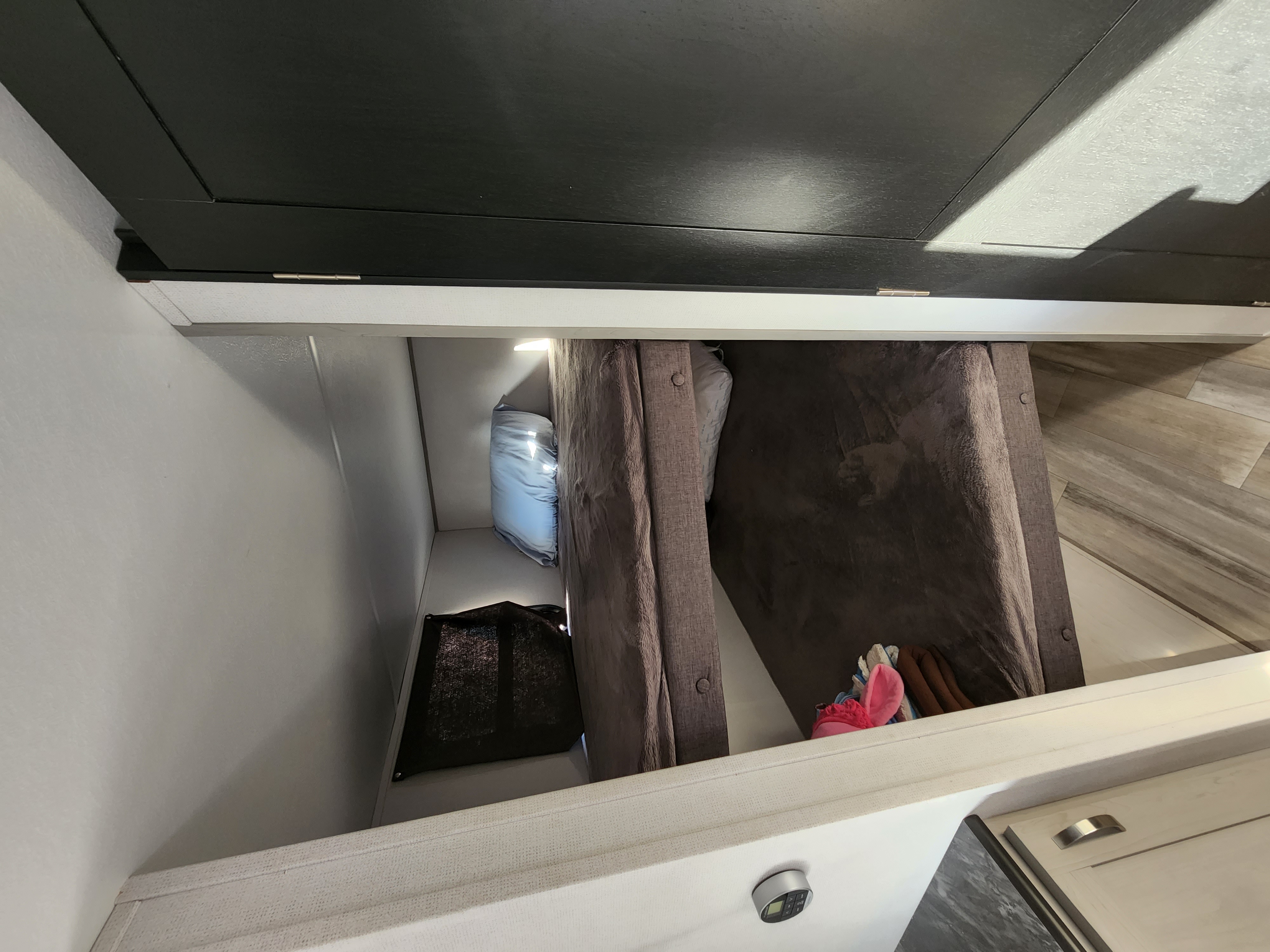 rv rental interior: a neat bunk bed space, open storage with light, and a lower cabinet with control panel.. Prime Time Tracer 2021