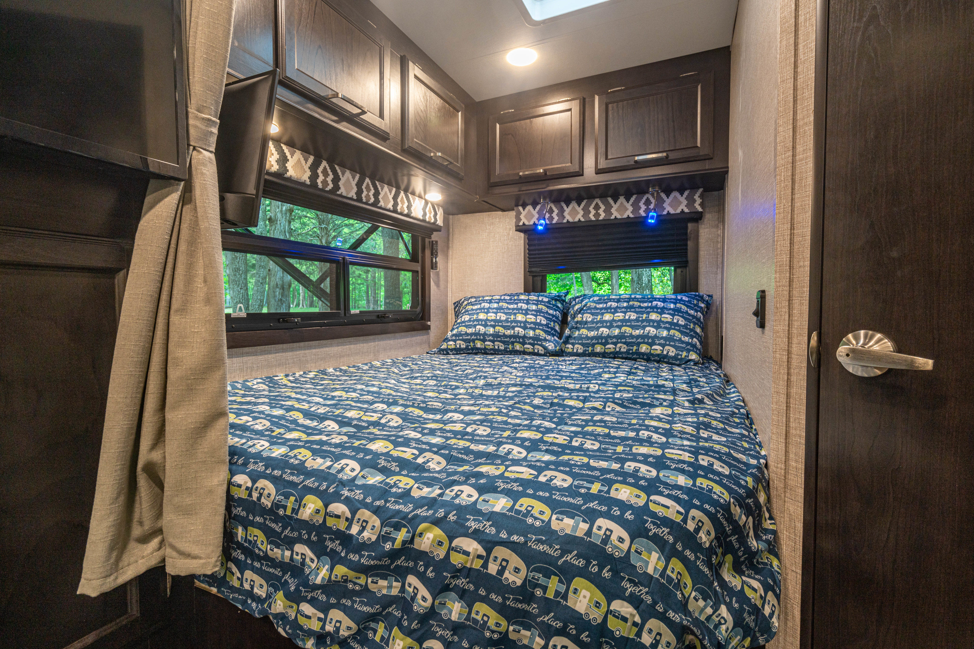 **RV rental**: Cozy bedroom with a unique camper-patterned bedspread & pillows, TV, and scenic window views.. Entegra Coach Odyssey 25R 2022