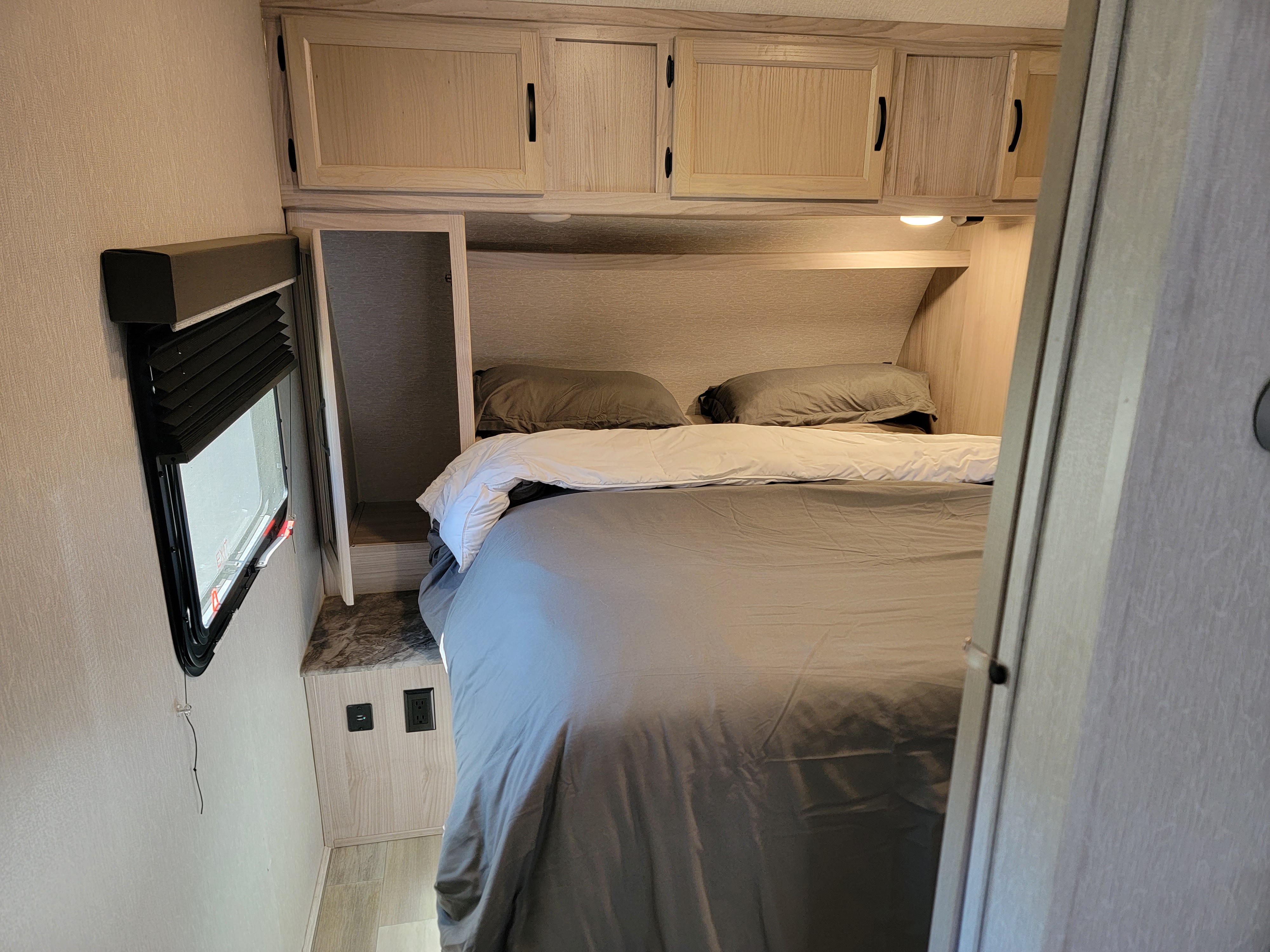 Relax in this inviting RV rental bedroom. It features a comfy bed, overhead cabinets, a window, and outlets.. Coachmen Spirit Ultra Lite 2021