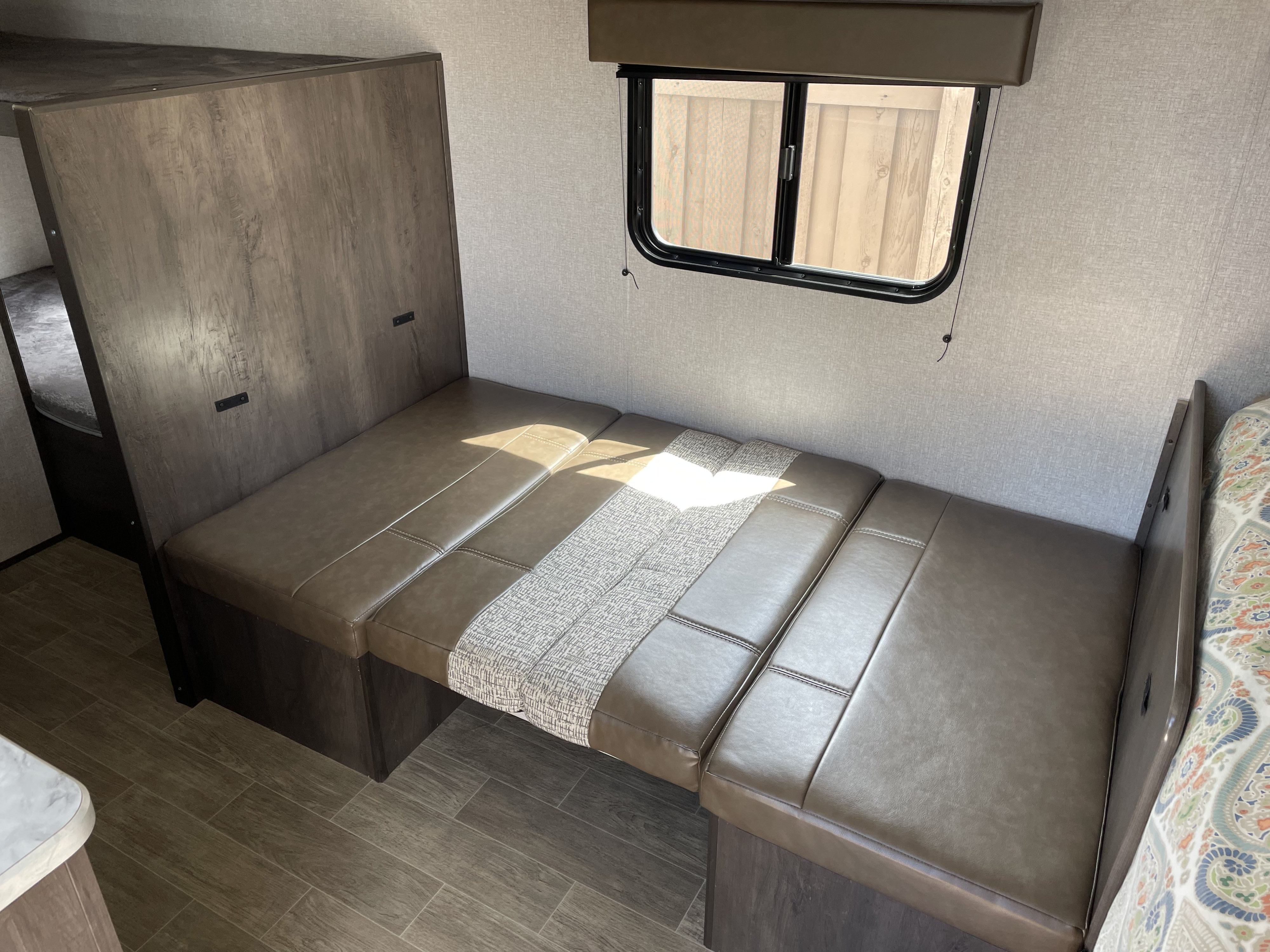 RV rental: Interior of a modern dinette with brown faux leather seating, a window, and a glimpse of bunk beds.. Dutchmen Coleman Lantern LT 2020