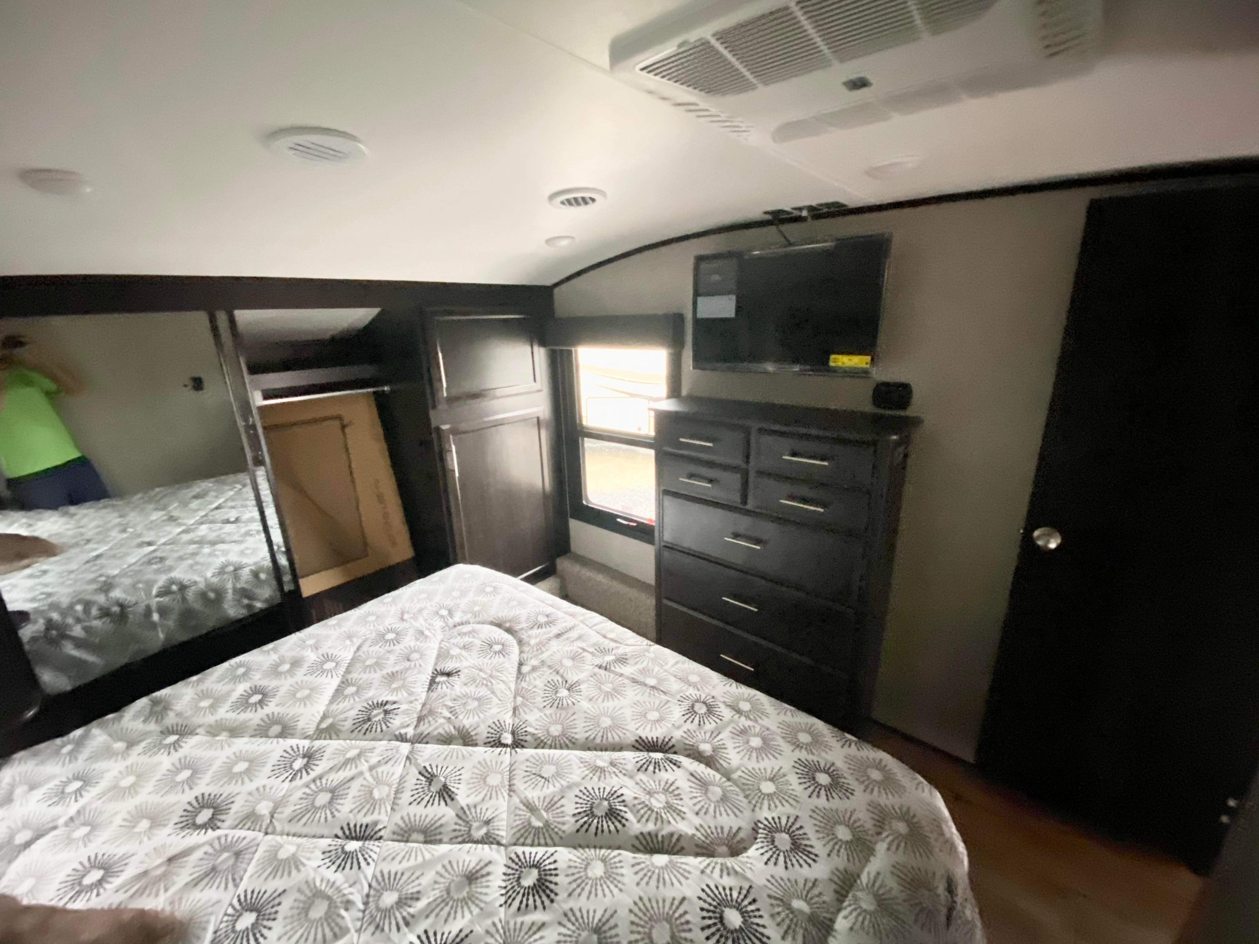 A cozy RV rental bedroom featuring a comfortable bed, TV, dresser, mirrored closet, and ceiling AC unit.. Jayco Eagle 2021