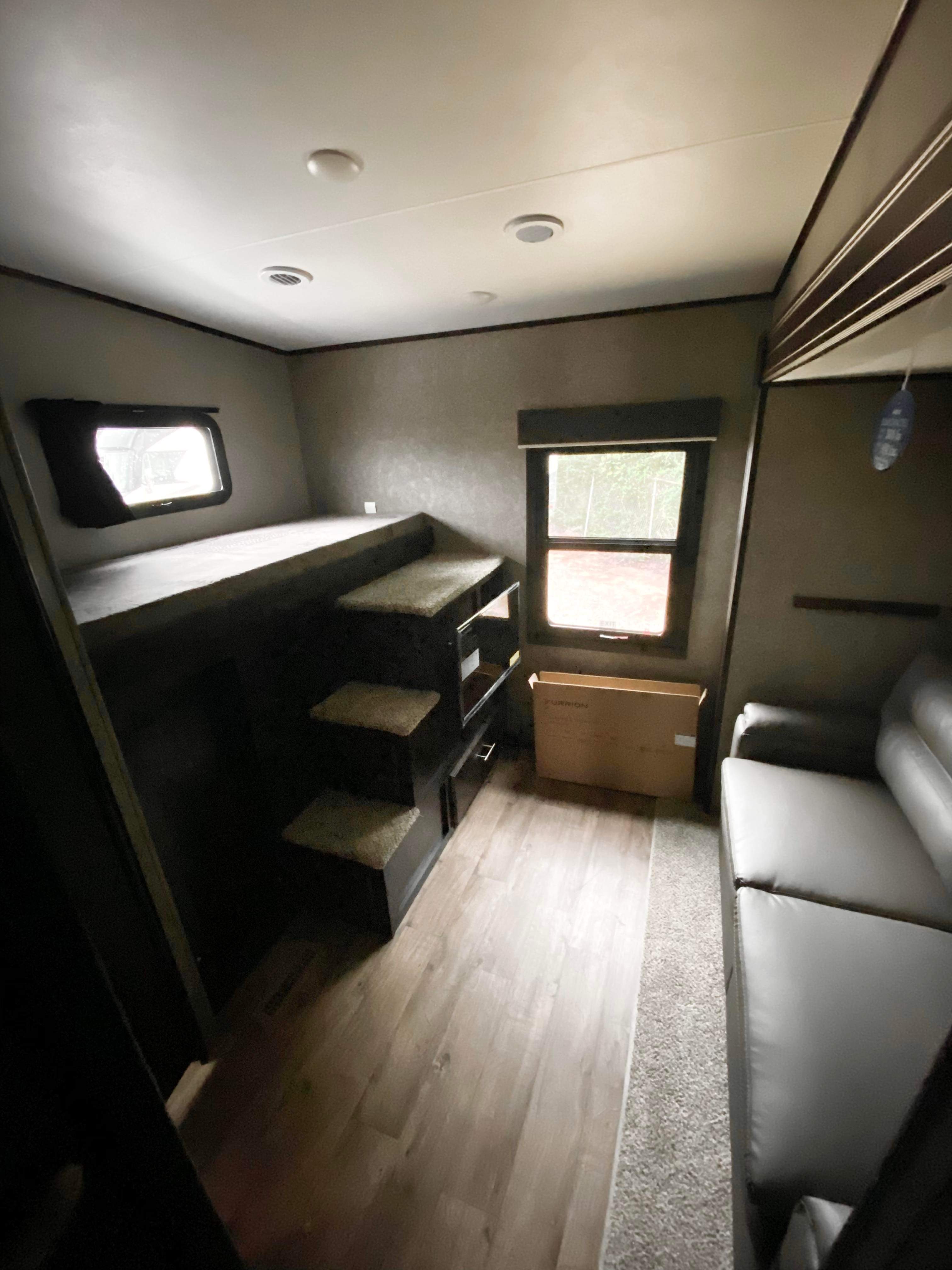 Modern RV rental interior: bunk bed with steps, comfortable sofa, and windows for natural light.. Jayco Eagle 2021