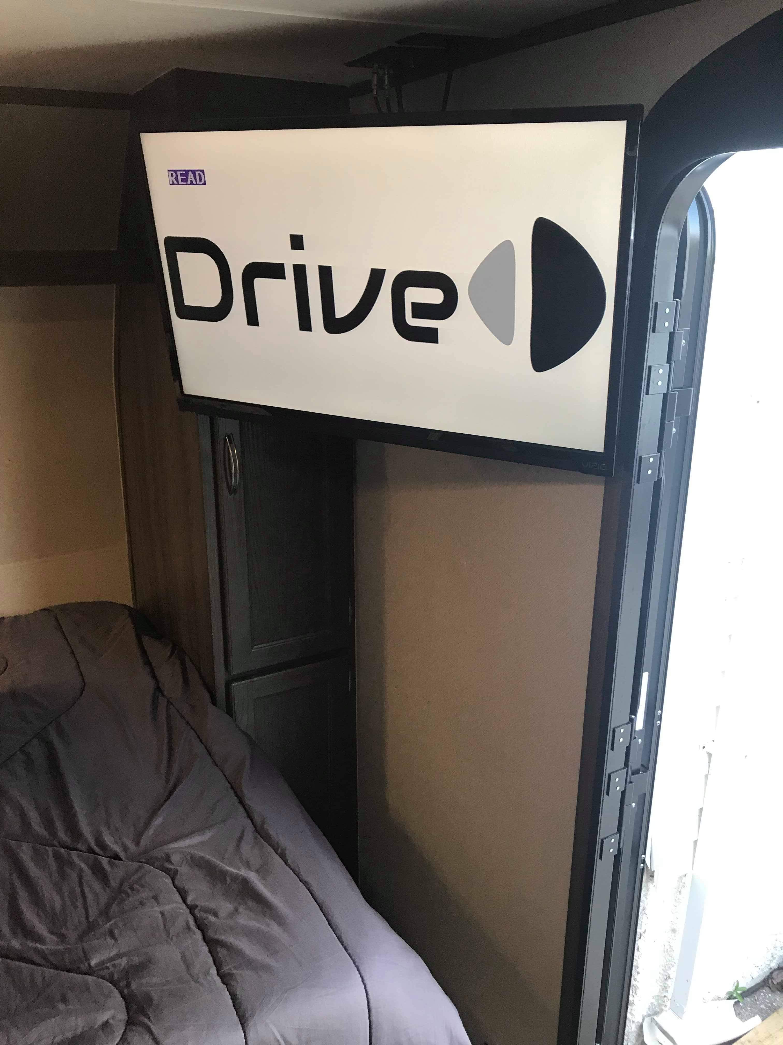 Inside an RV rental: a ceiling-mounted TV, cozy bed, and storage cabinets optimize this compact interior.. Riverside Travel Trailer Dream 2018