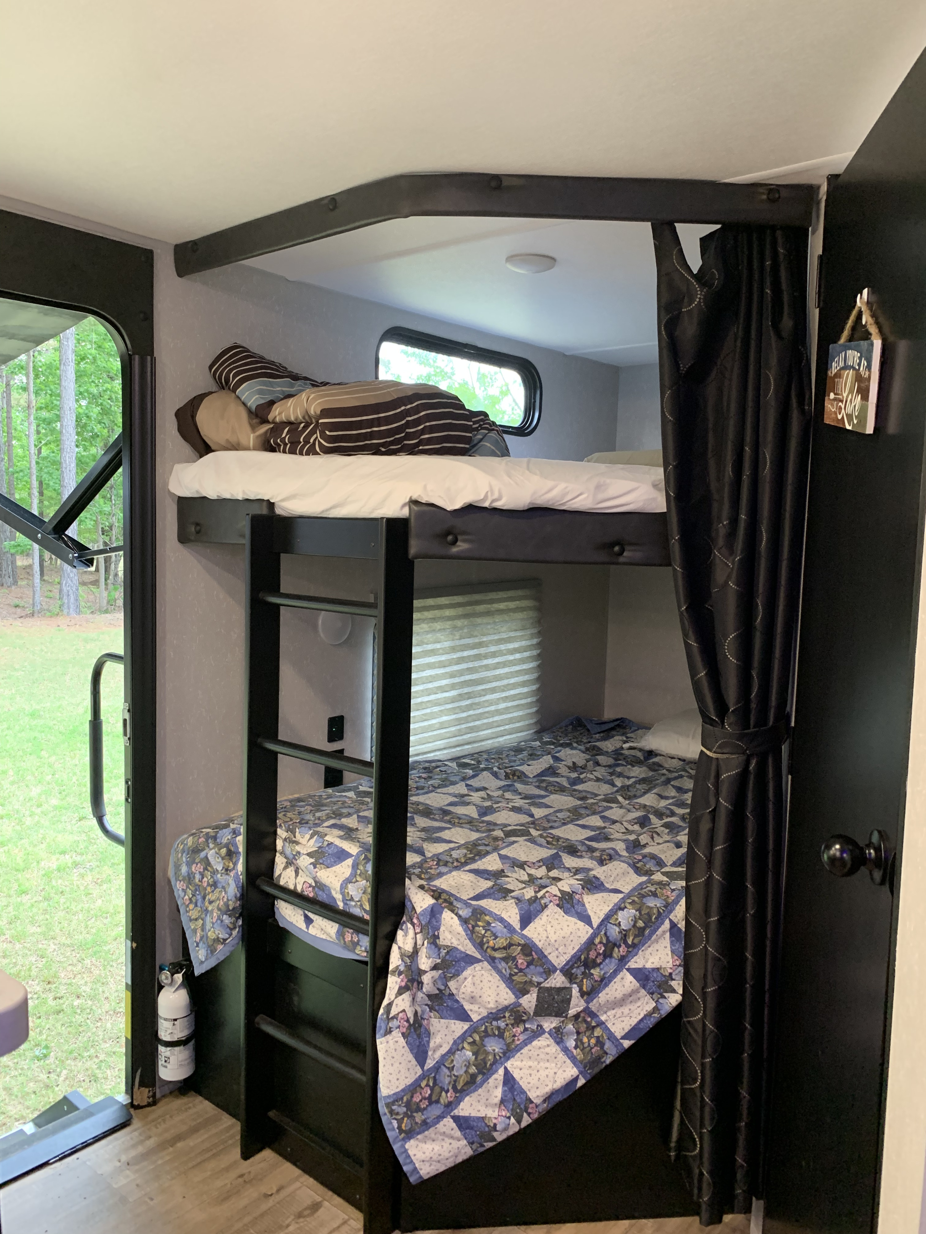 Cozy bunk beds in an RV rental interior, with ladder, window, and outdoor view. Ideal for family camping.. Forest River Cherokee 2021
