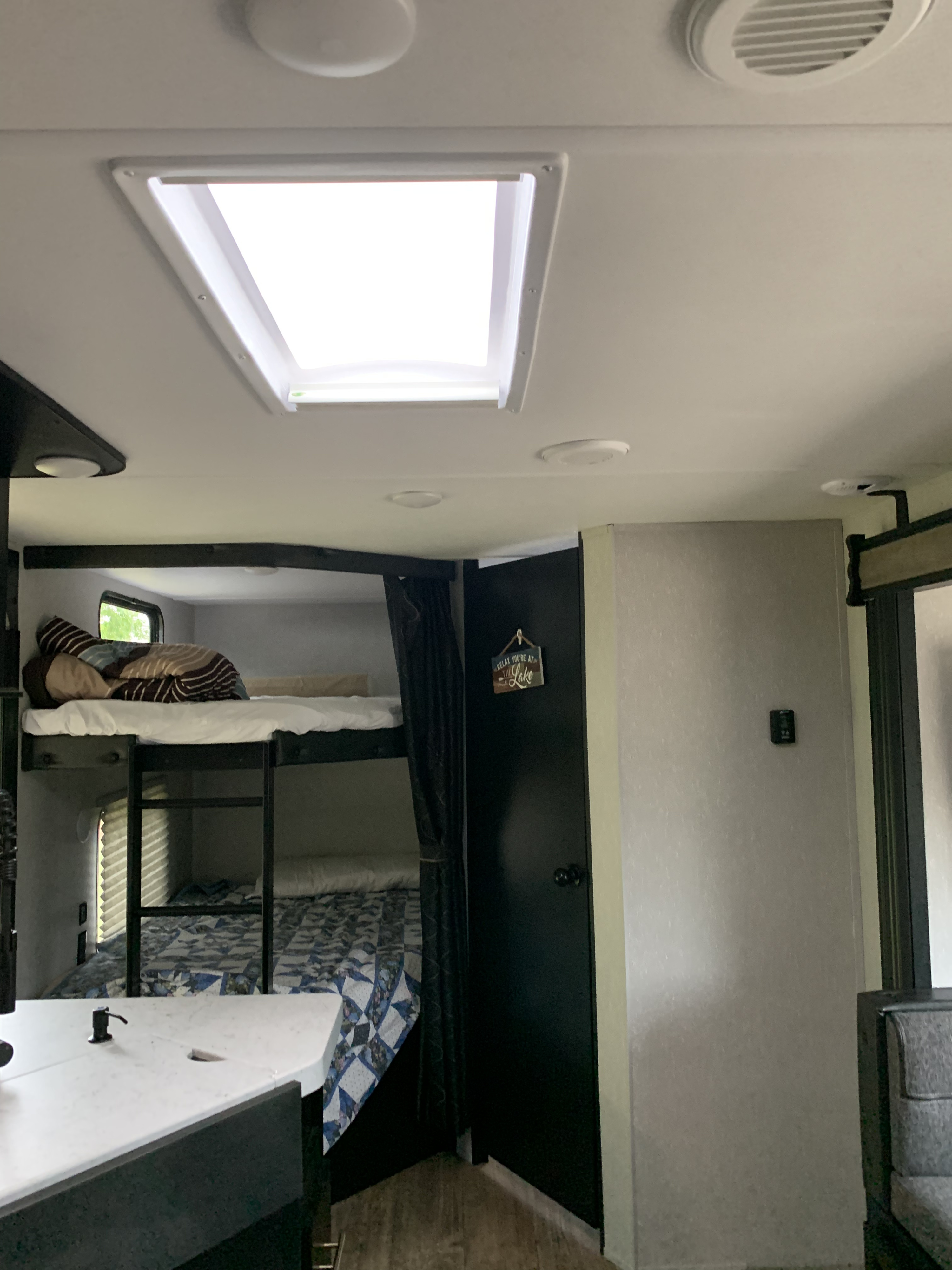 Spacious RV rental interior featuring cozy bunk beds, a bright skylight, and comfortable amenities for family adventures.. Forest River Cherokee 2021