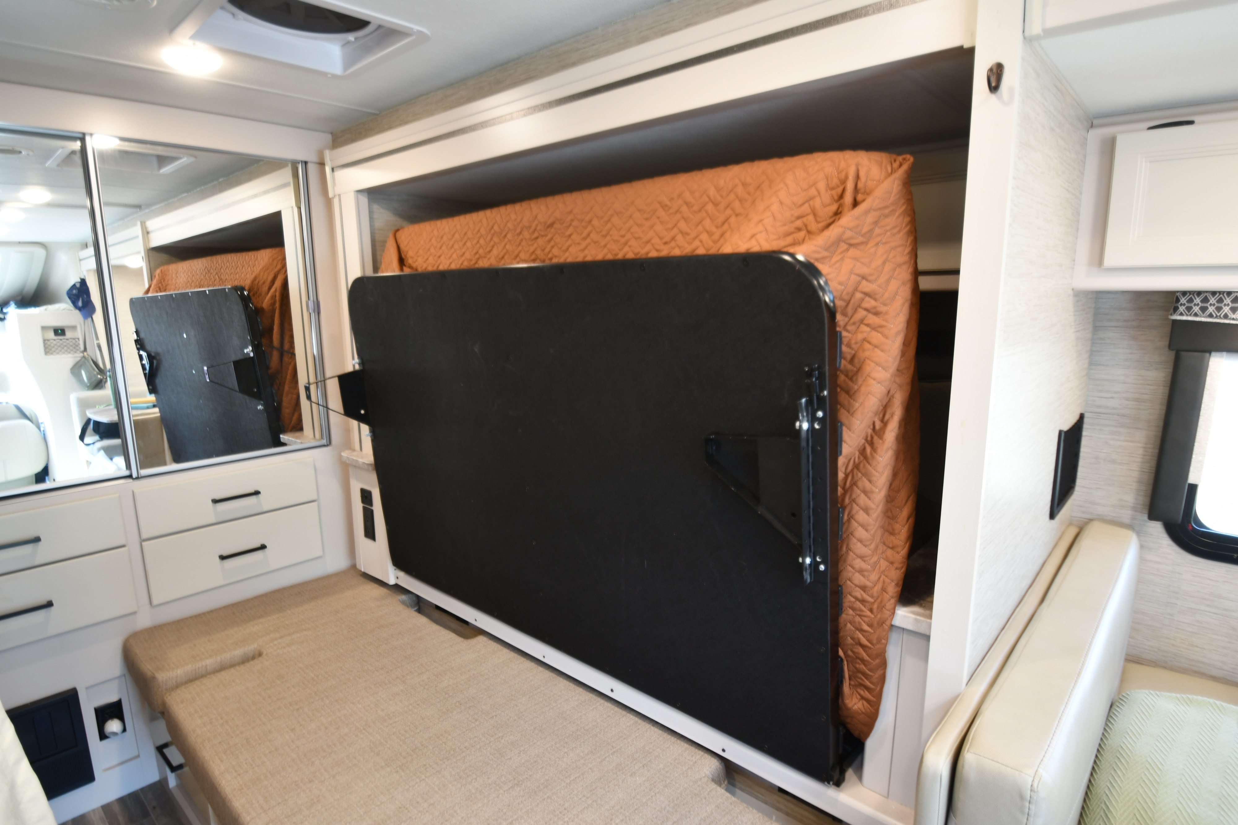 This RV rental interior showcases a cleverly folded-up bed, revealing a cozy seating area and storage for efficient space use.. Thor Compass 2022