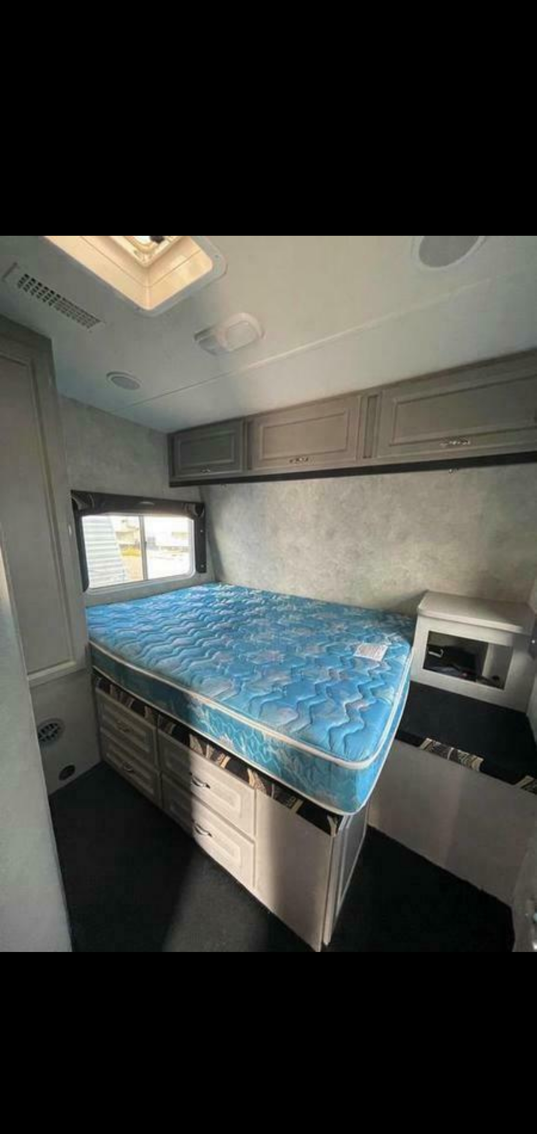 Compact RV rental bedroom featuring a blue mattress over built-in storage drawers and overhead cabinets.. Weekend Warrior Widelite Wlfsc2800 2009