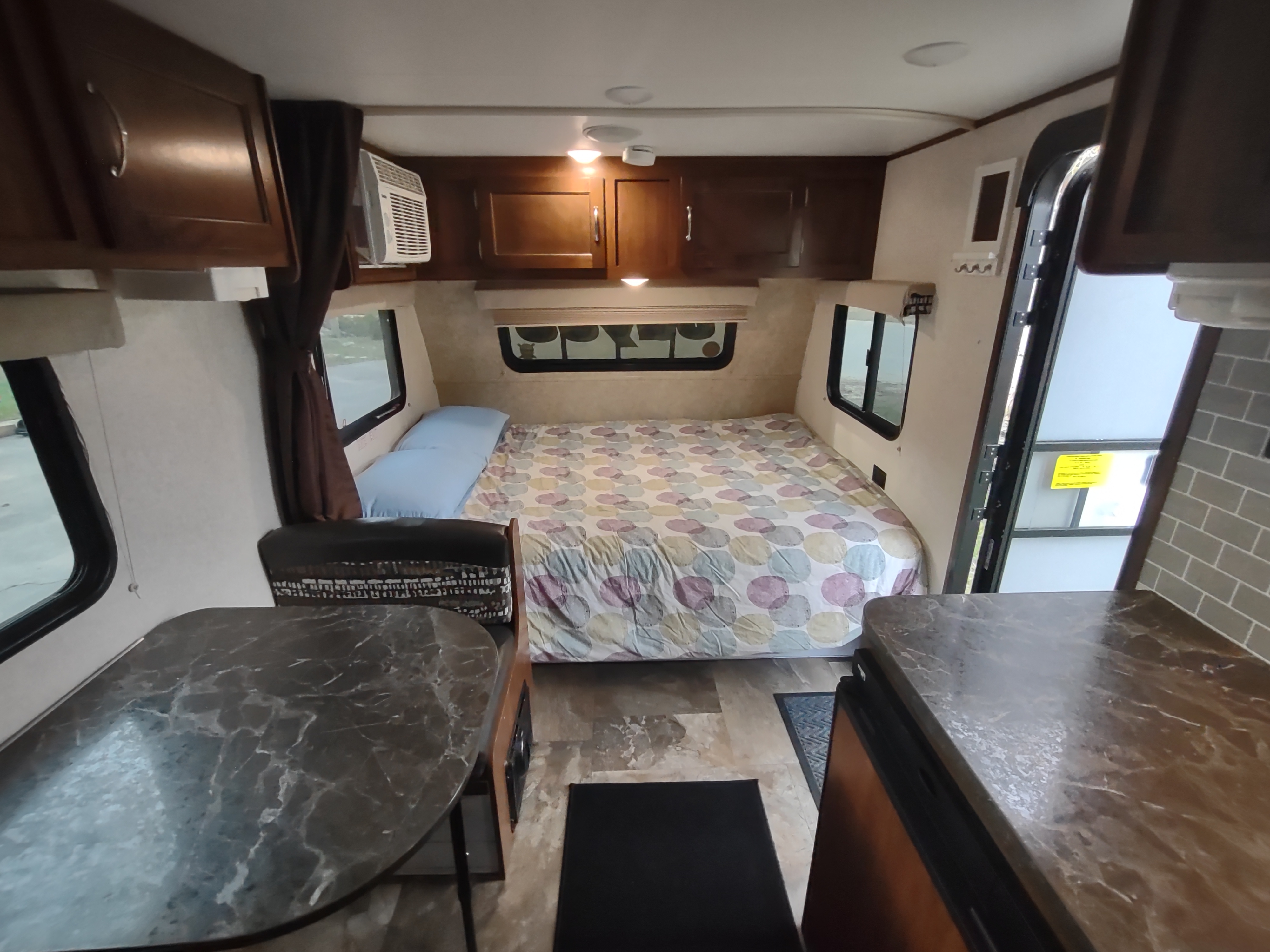 Spacious RV rental interior featuring a bed with patterned comforter, dining table, and kitchen counter for a cozy travel living space.. Jayco Jay Flight SLX 2017