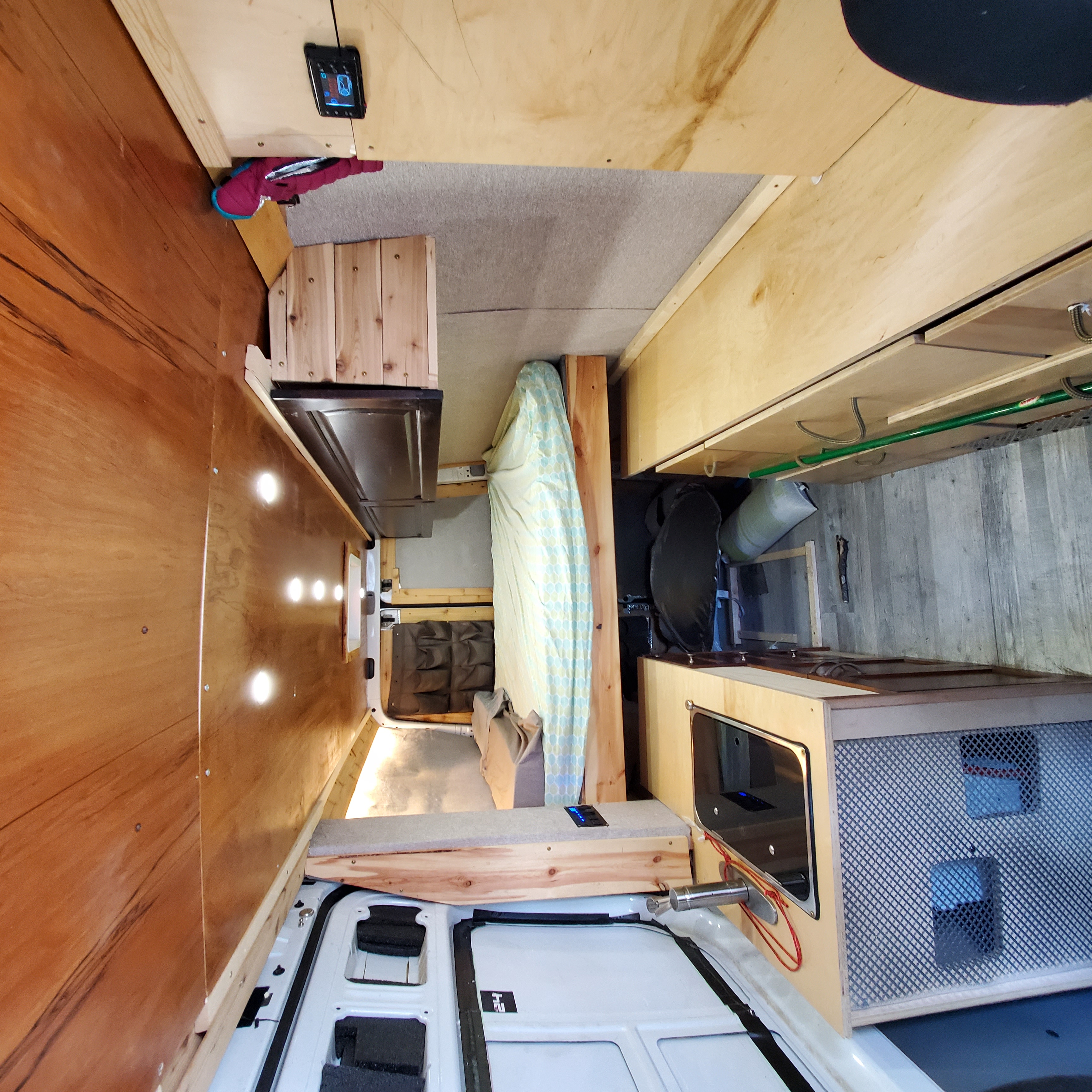 Spacious and well-appointed RV rental interior, featuring a cozy bed, compact kitchen, and custom wood finishes.. Mercedes-Benz B class campervan MB 140 2011