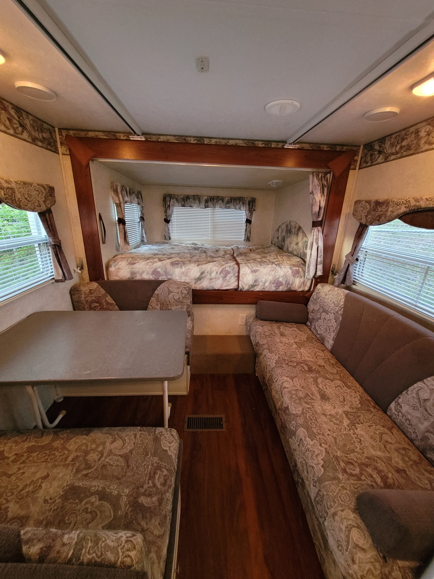 Explore this inviting RV rental interior: a comfortable bed, dining area, and sofa create a perfect mobile living space.. Keystone RV Outback 2009