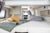 Interior of an RV rental camper van: a cozy bed with pillows and a blanket, ready for your road trip comfort.. NOMAD COMPACT FONT VENDOME 2023