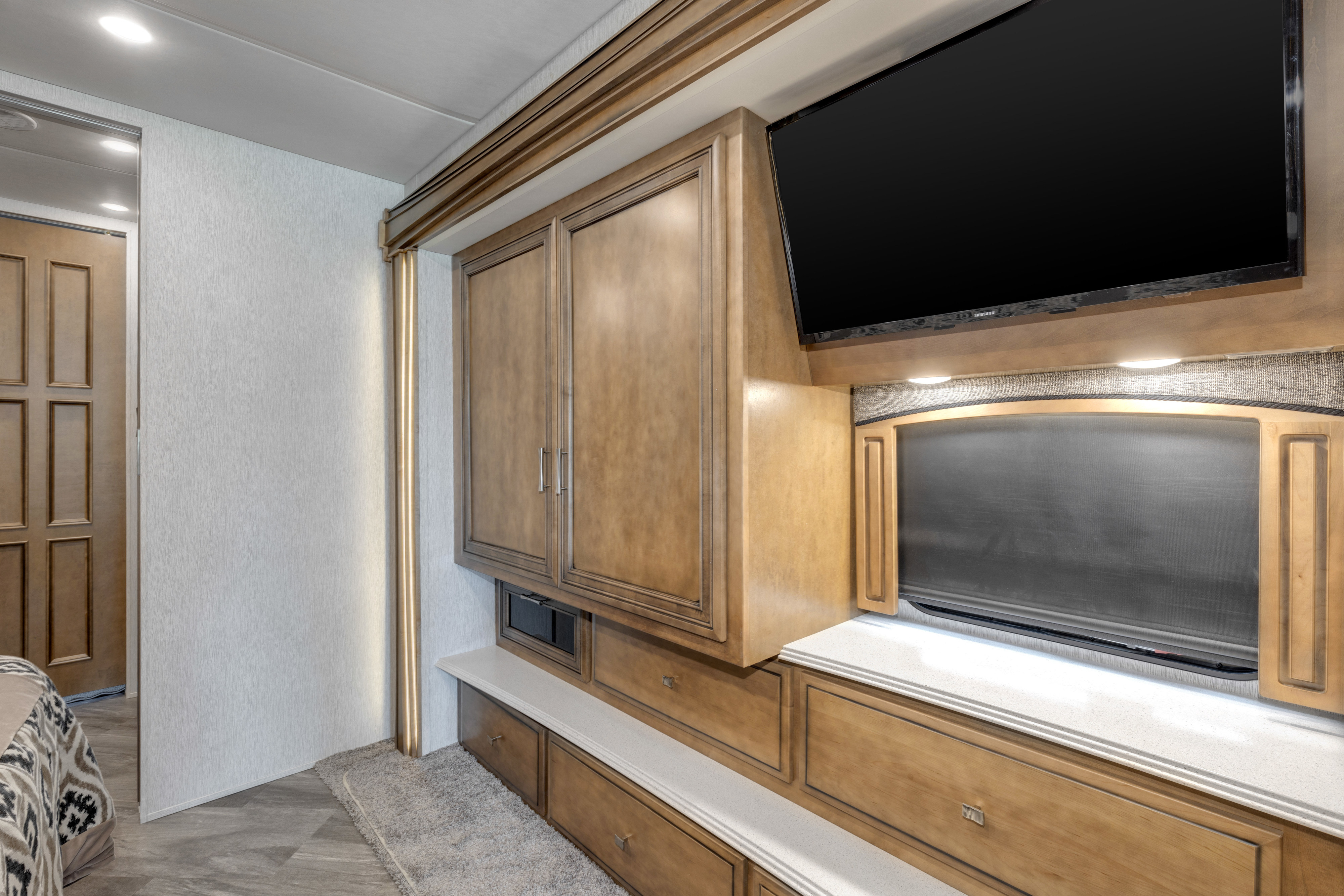Modern rv rental bedroom with wall-mounted TV, built-in wooden storage, and illuminated window feature.. Other Canyon Star 2020