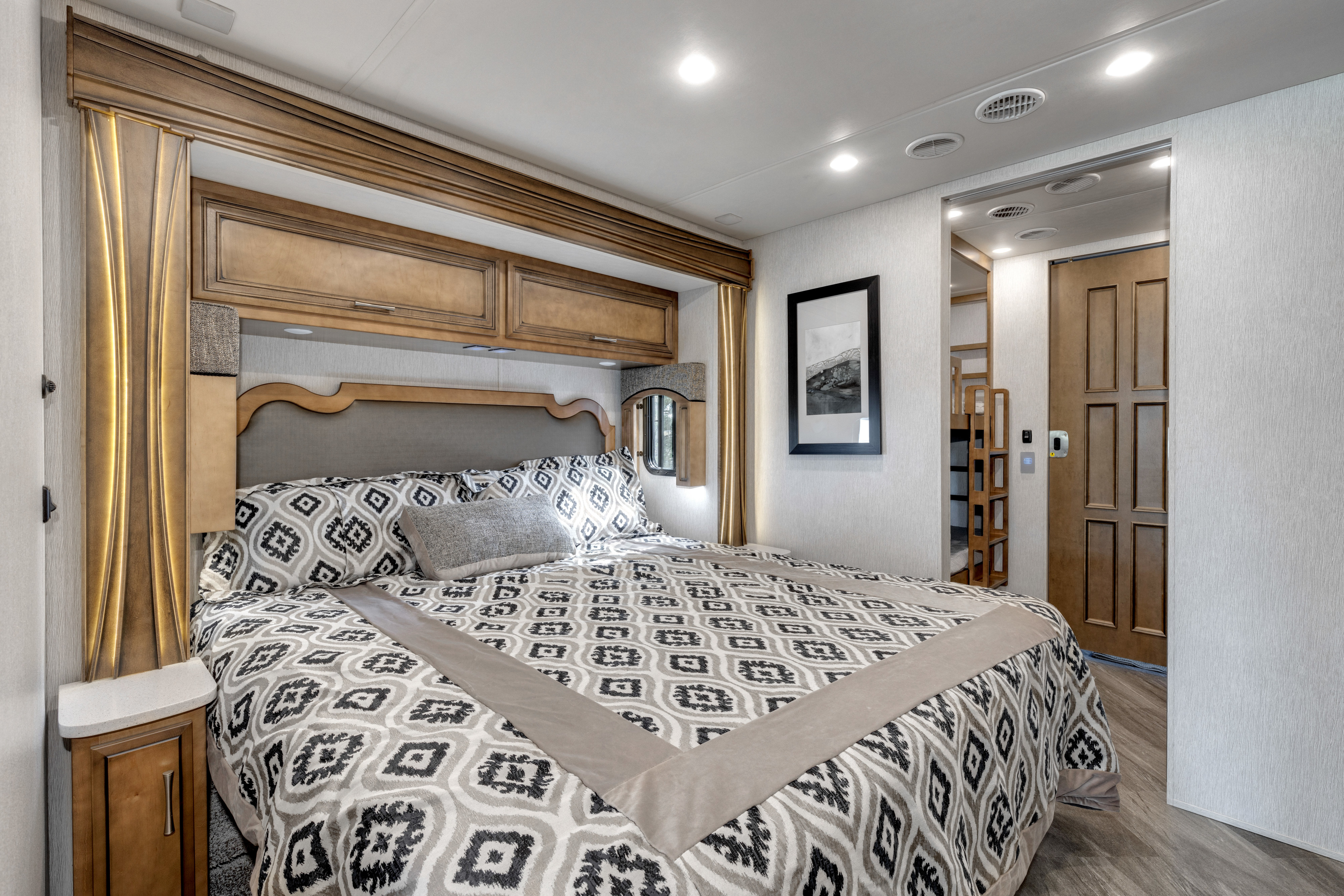 Comfortable RV rental bedroom featuring a large bed with patterned bedding, overhead storage, and an adjacent bunk area, ideal for family travel.. Other Canyon Star 2020