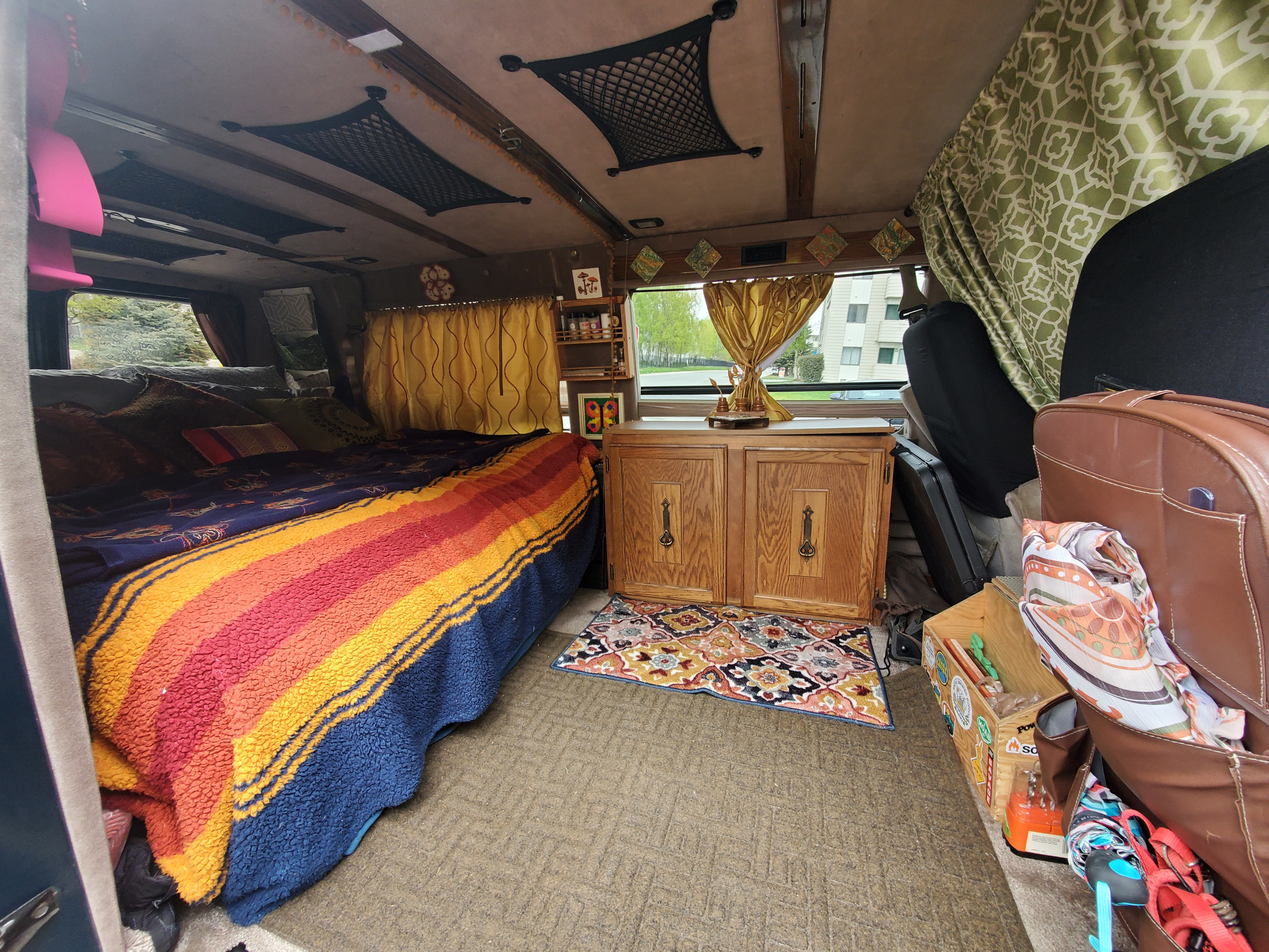 Cozy RV rental interior with a bed, wooden cabinet, and clever storage solutions, ideal for adventurous travel.. Chevrolet G-20 1995
