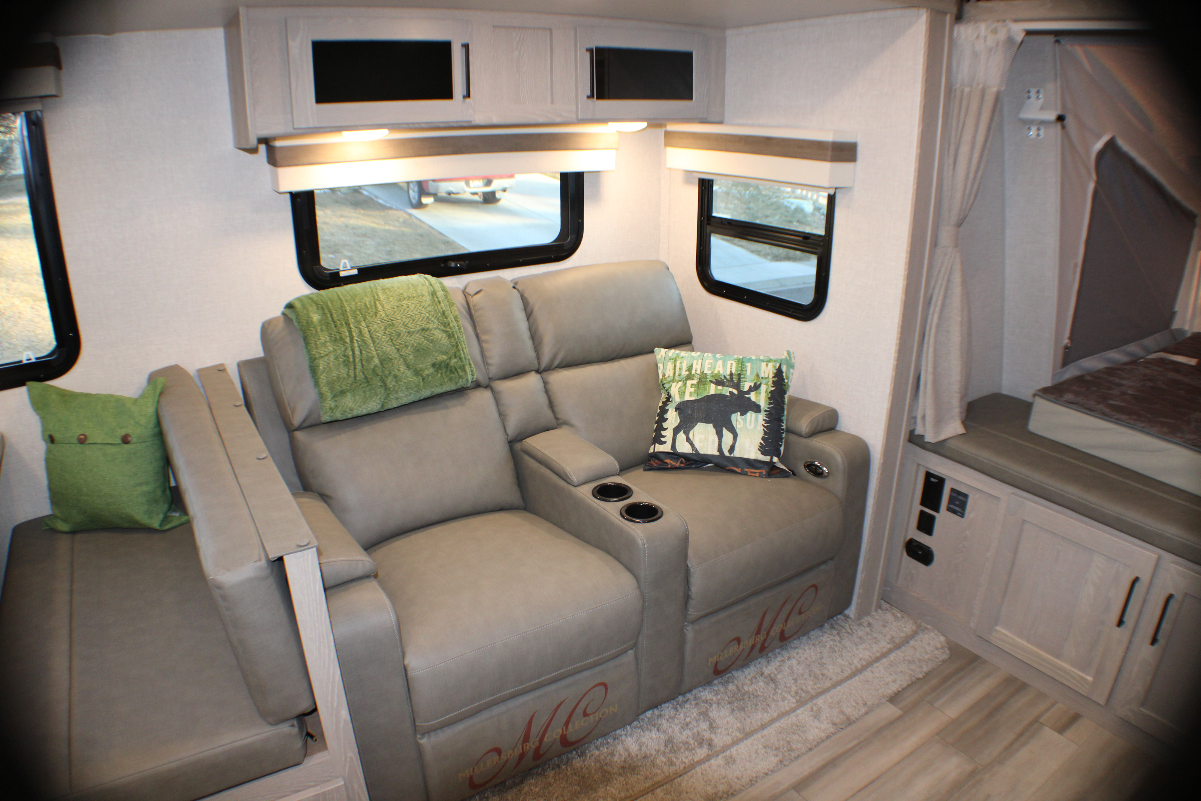 Spacious rv rental interior with light grey reclining seats, cup holders, overhead cabinets, and a pop-out bed.. Forest River Rockwood Roo 2022