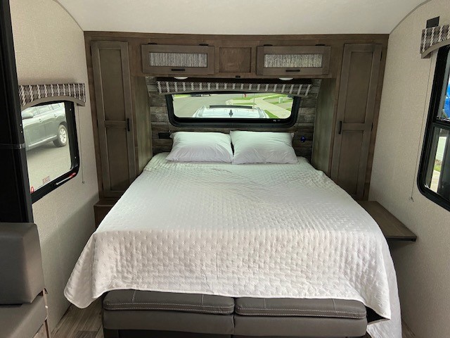 RV rental: Comfortable bedroom featuring a large bed, windows, and overhead cabinets.. Venture 4ezt22329n4011299 2022
