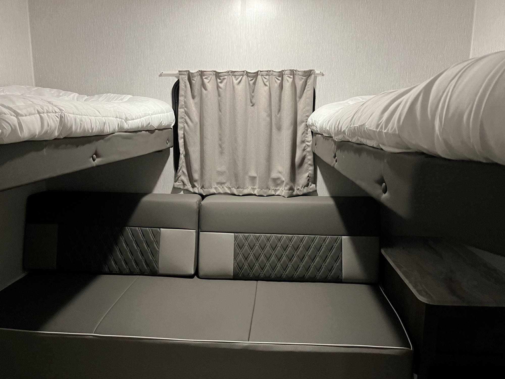 RV rental interior featuring two bunk beds above a gray upholstered seating area and a central privacy curtain.. Forest River Salem Cruise Lite 2022