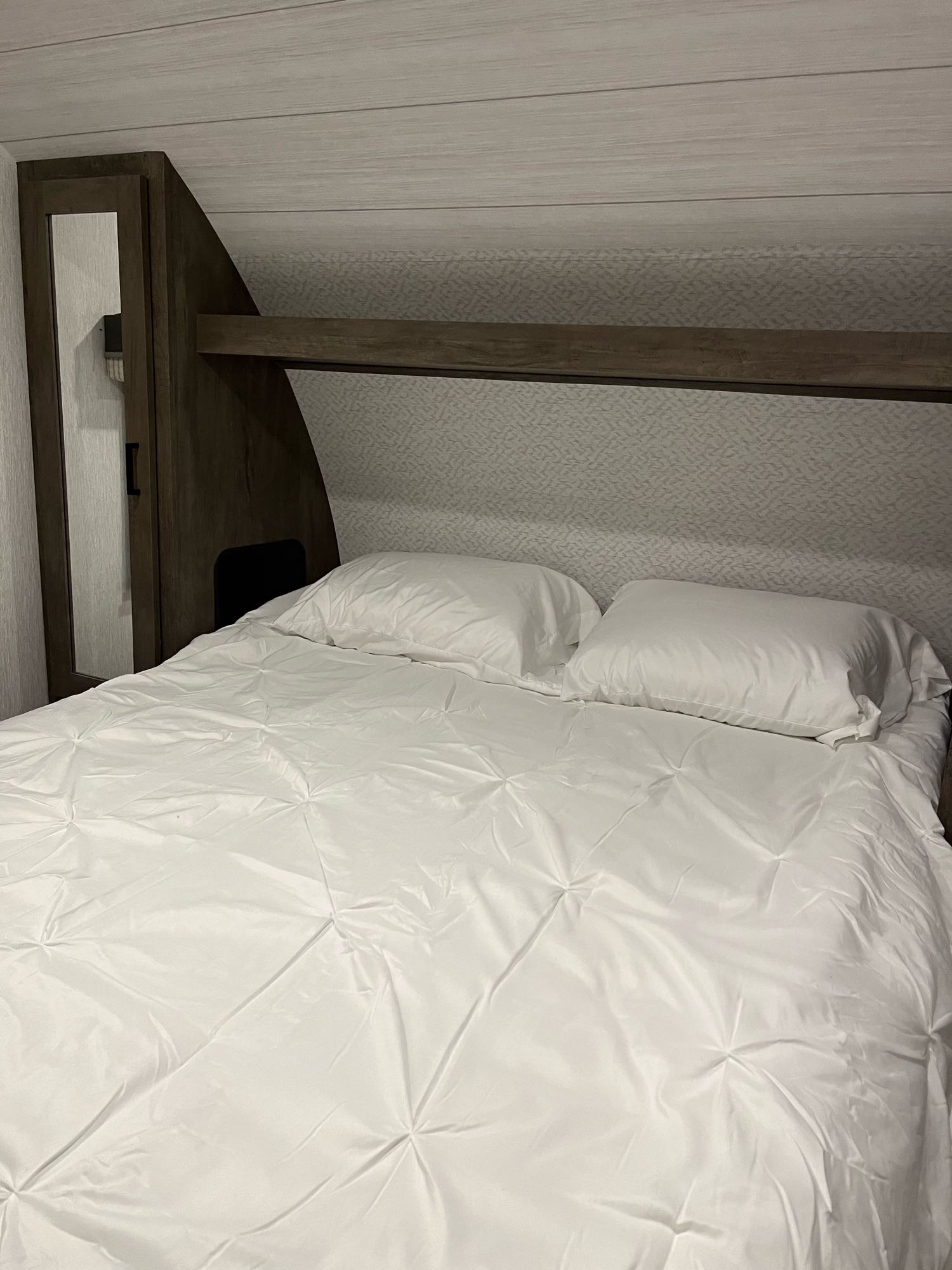 Comfortable rv rental bedroom with a large bed, fresh white bedding, built-in headboard, and compact storage in a modern interior.. Forest River Salem Cruise Lite 2022