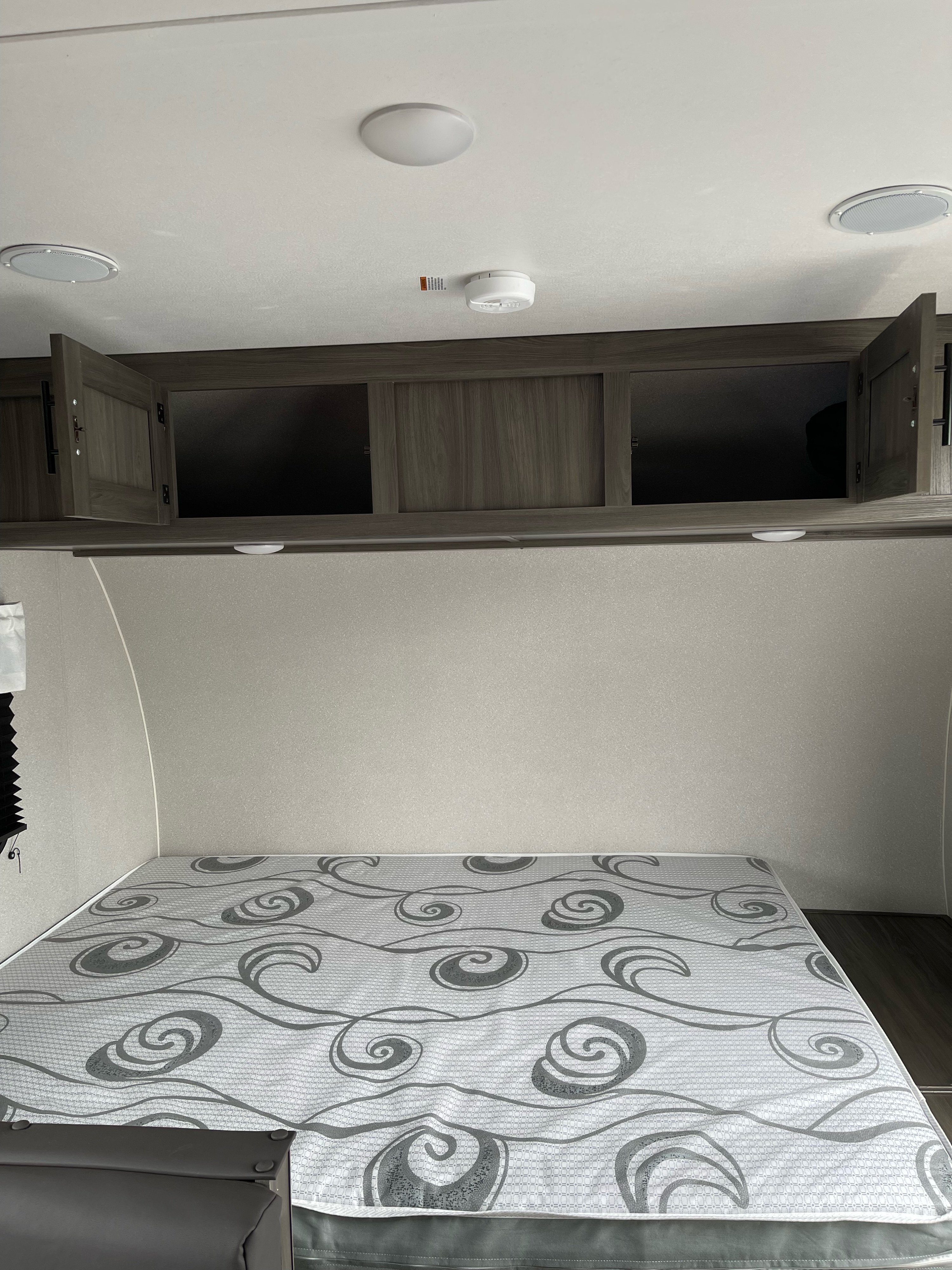 RV rental bedroom: a comfortable mattress, open overhead cabinets, ceiling lights, and speakers for your journey.. Forest River Shasta 2021