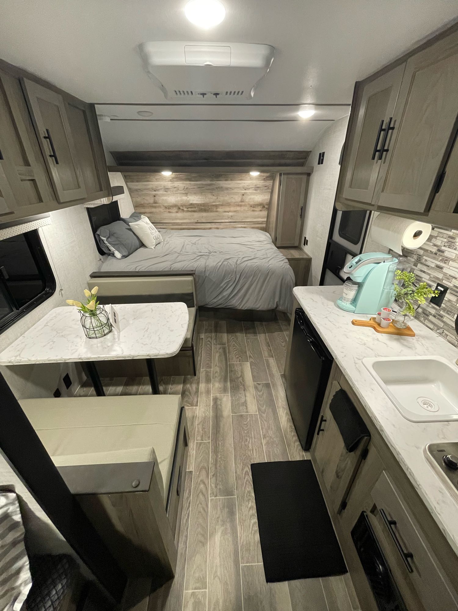 Cozy, modern RV rental interior featuring a bed, dinette, and kitchen. Ideal for compact living and travel.. Gulf Stream Enlighten 18BH 2022