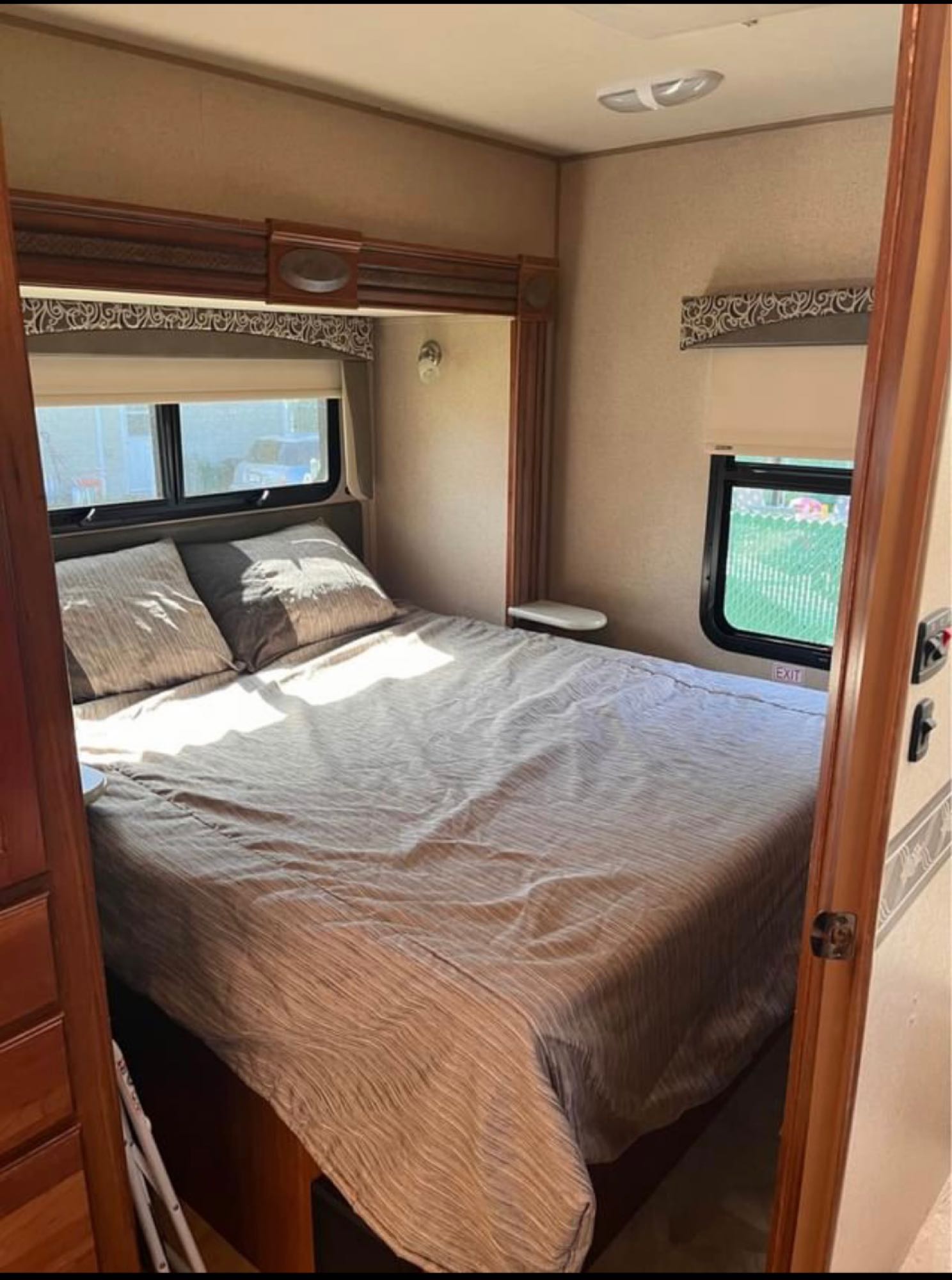 Cozy RV rental bedroom features a comfortable bed, bathed in natural light from windows, offering a restful escape.. Jayco Redhawk 2016