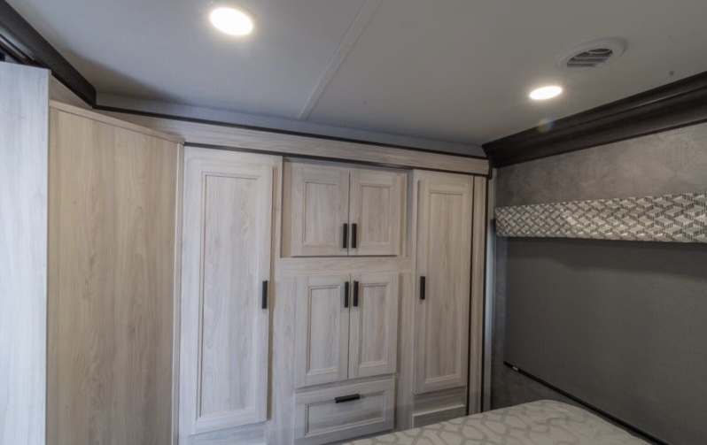 Spacious RV rental bedroom features light wood built-in cabinets, wardrobes, and modern storage for a comfortable journey.. Forest River Forester 2022