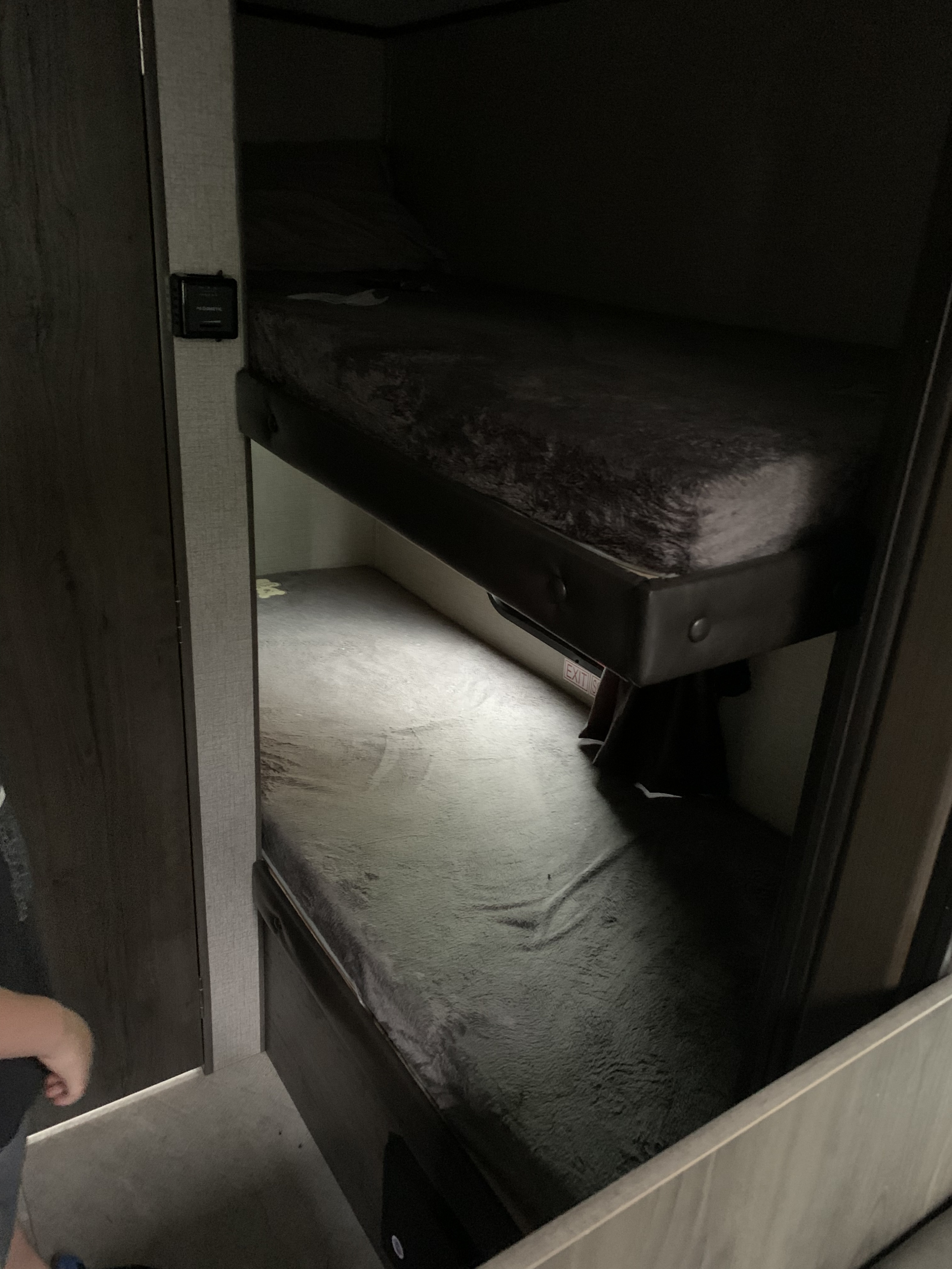 Cozy bunk beds in an RV rental interior, featuring dark mattresses and a visible "EXIT" sign for a compact sleeping area.. Jayco Jay Flight 2020
