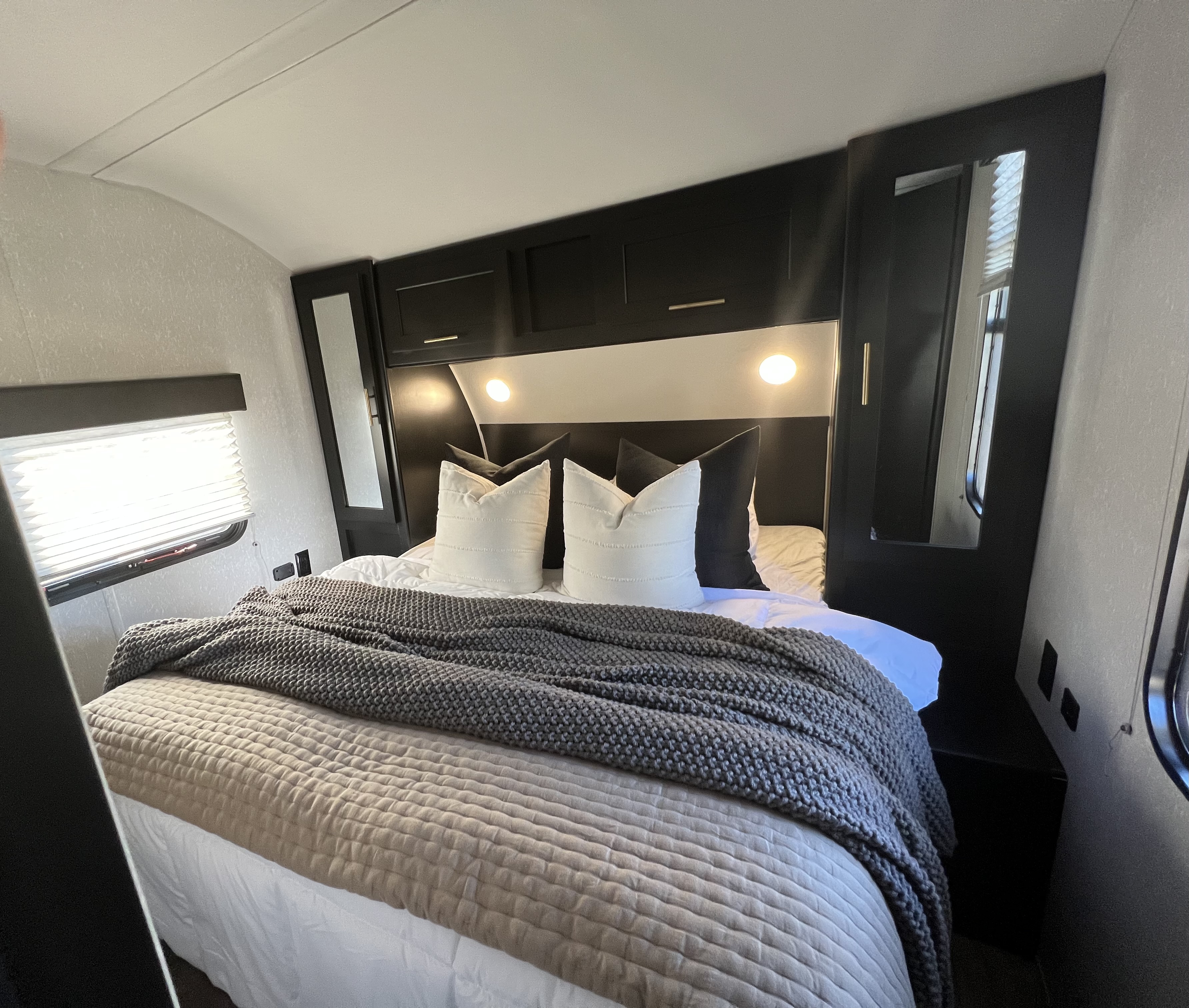 Cozy RV rental bedroom with a comfy bed, modern black headboard, integrated lighting, and mirrored storage cabinets.. Forest River Cherokee Grey Wolf 2021
