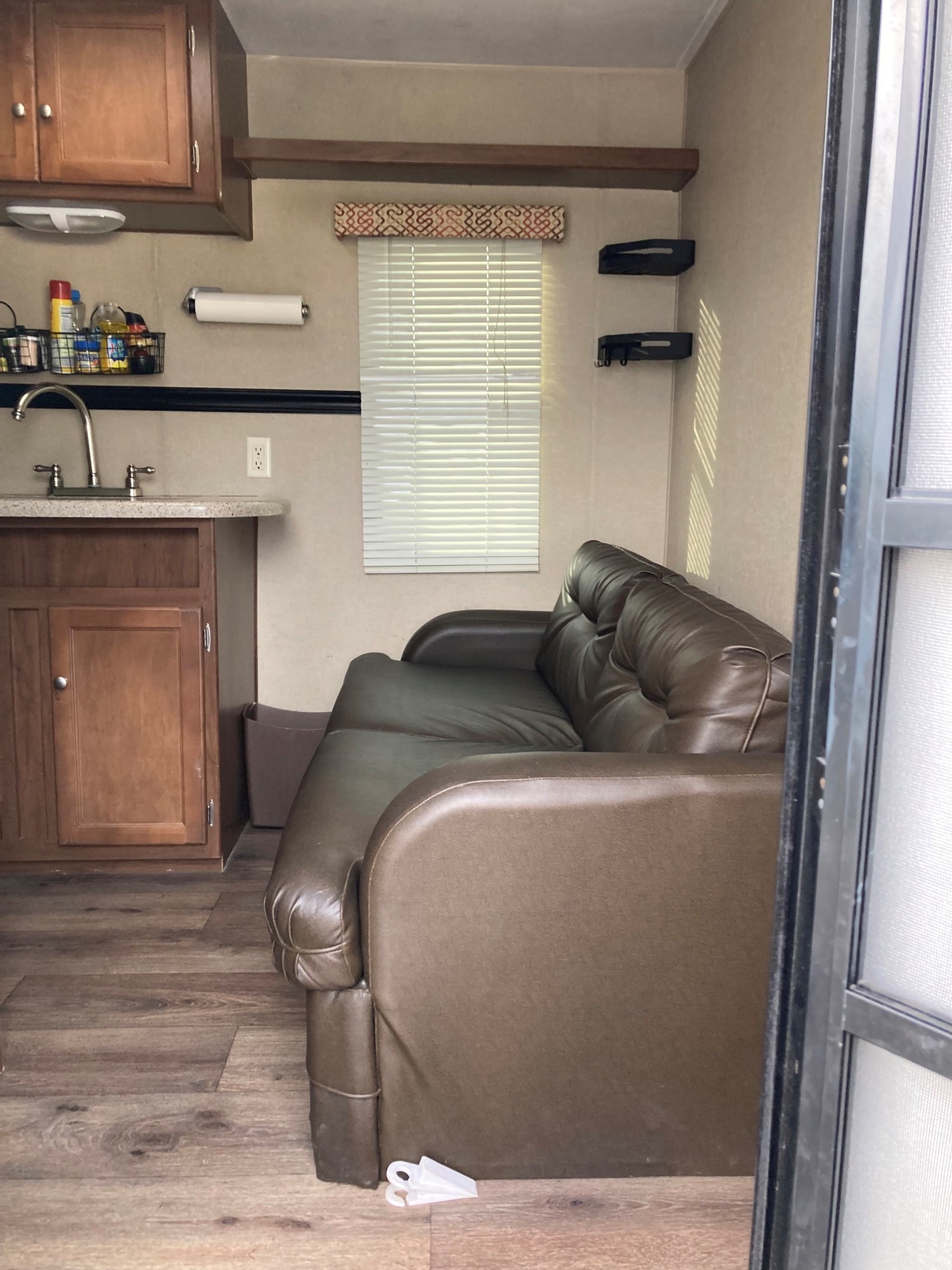Step inside this RV rental! Features a compact kitchen with a sink & cabinets, plus a cozy brown sofa and wood flooring.. Dutchmen Dutchmen Trailer 2014