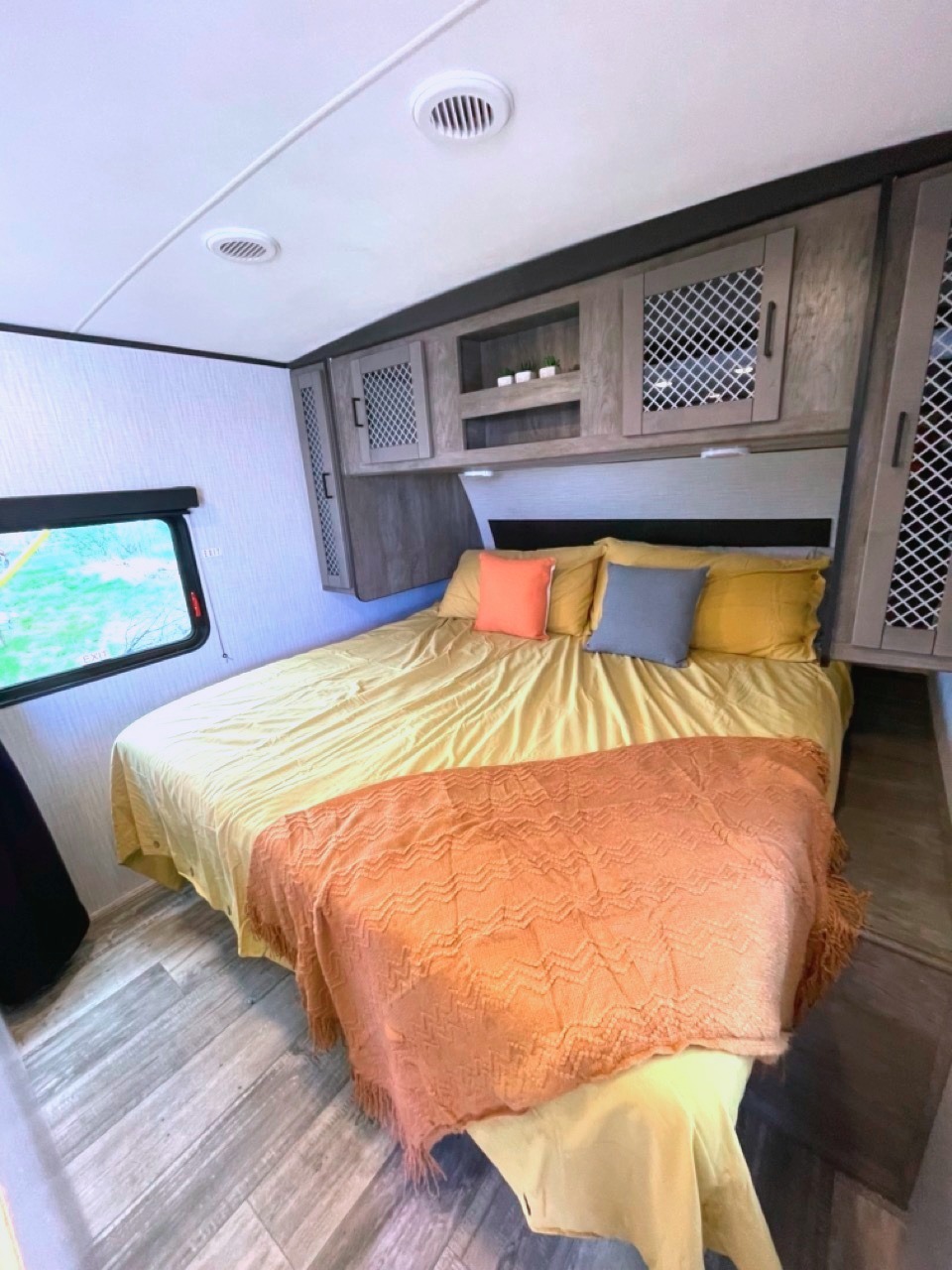 This inviting RV rental bedroom features a comfy bed, overhead storage, and large window. Ideal for your mobile adventures.. Heartland RVs North Trail 2021
