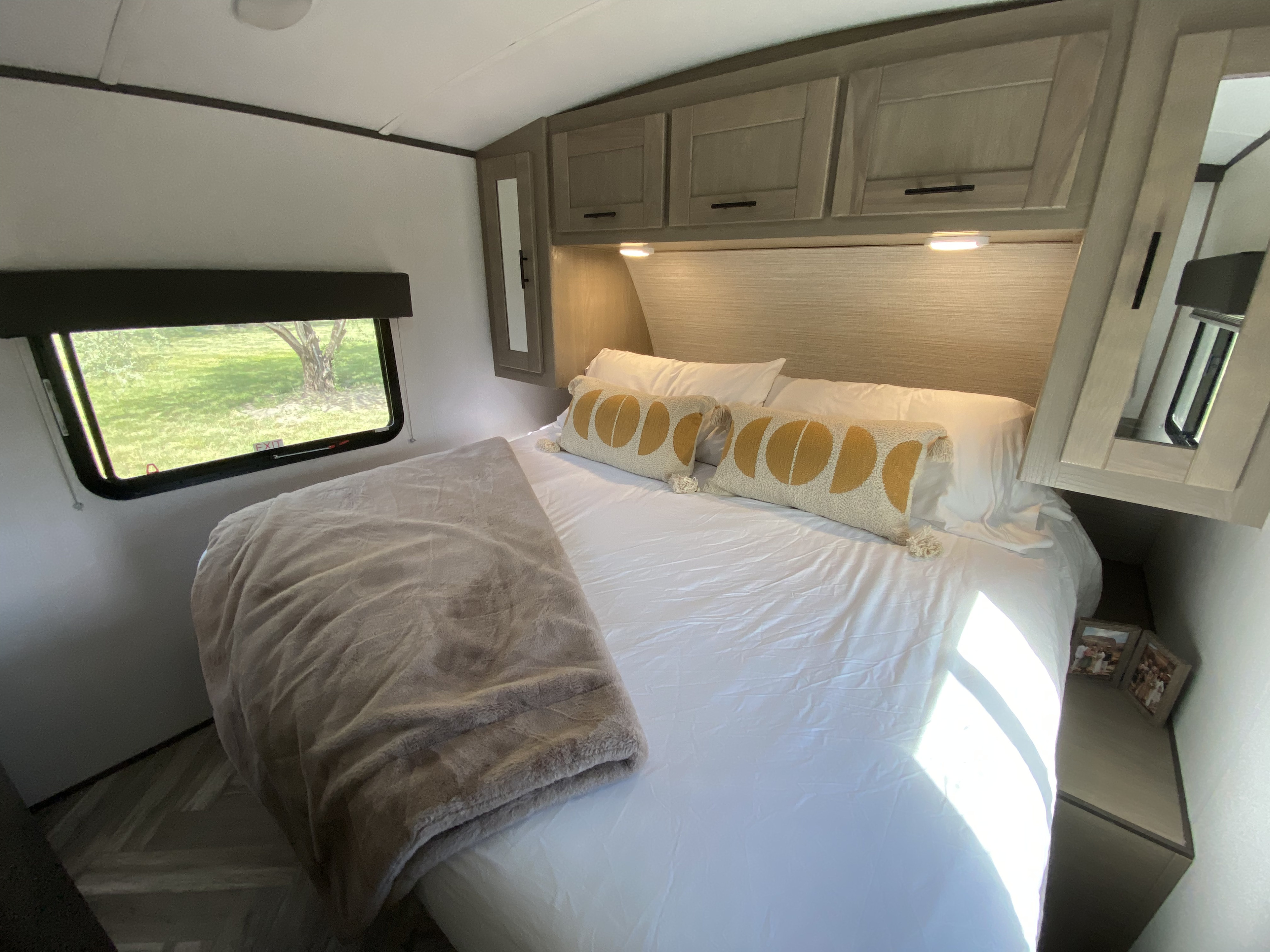 Cozy RV rental bedroom with comfortable bed, moon-pattern pillows, overhead cabinets, and scenic window view.. Cruiser RV M-277BHS 2021