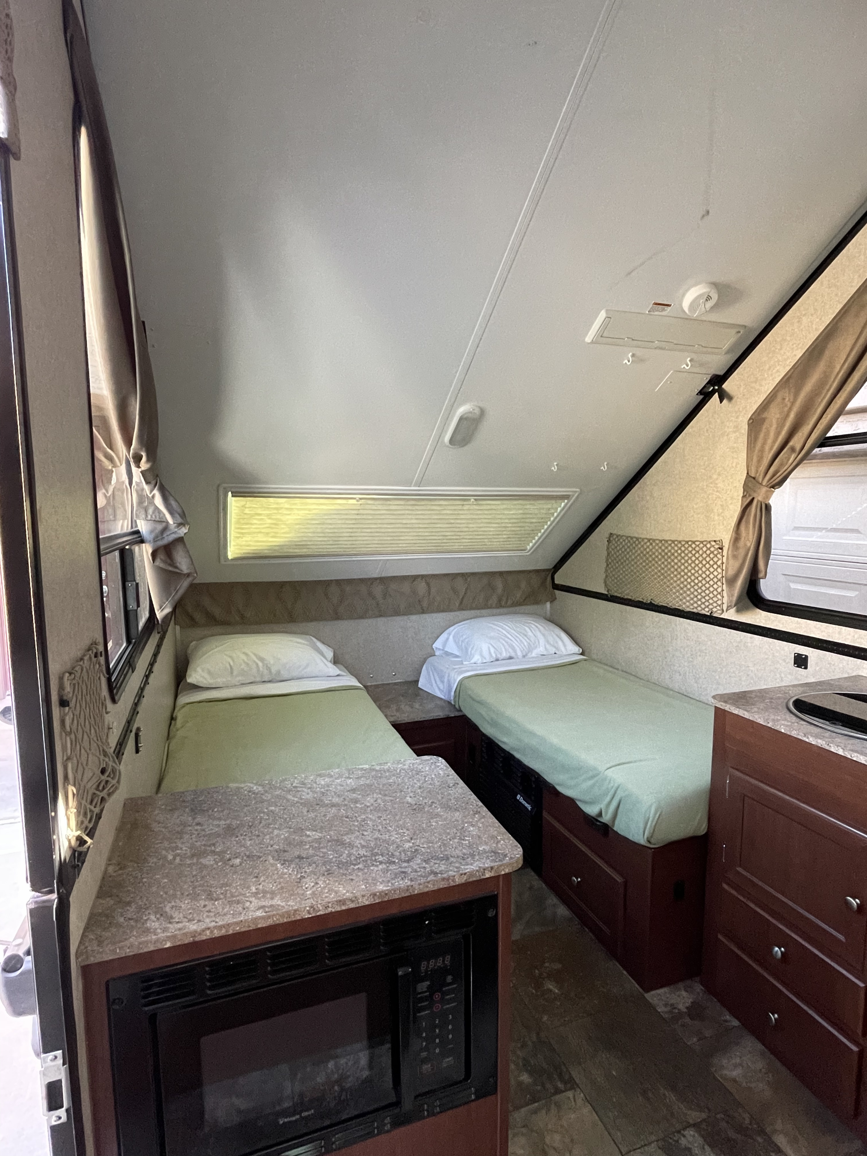 Cozy rv rental interior with two twin beds, a built-in microwave, and a compact kitchen area with countertop.. Forest River Flagstaff 2017