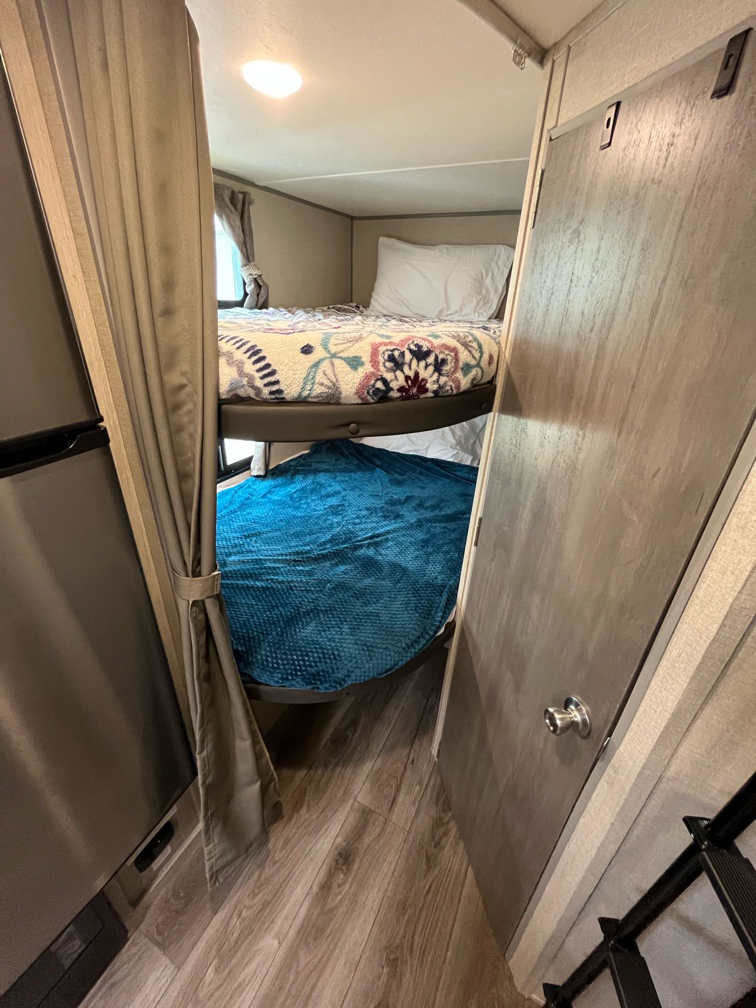 Explore this comfy RV rental interior with practical bunk beds, a fridge, and a door for compact living.. Coachmen Catalina Summit Series 7 2022