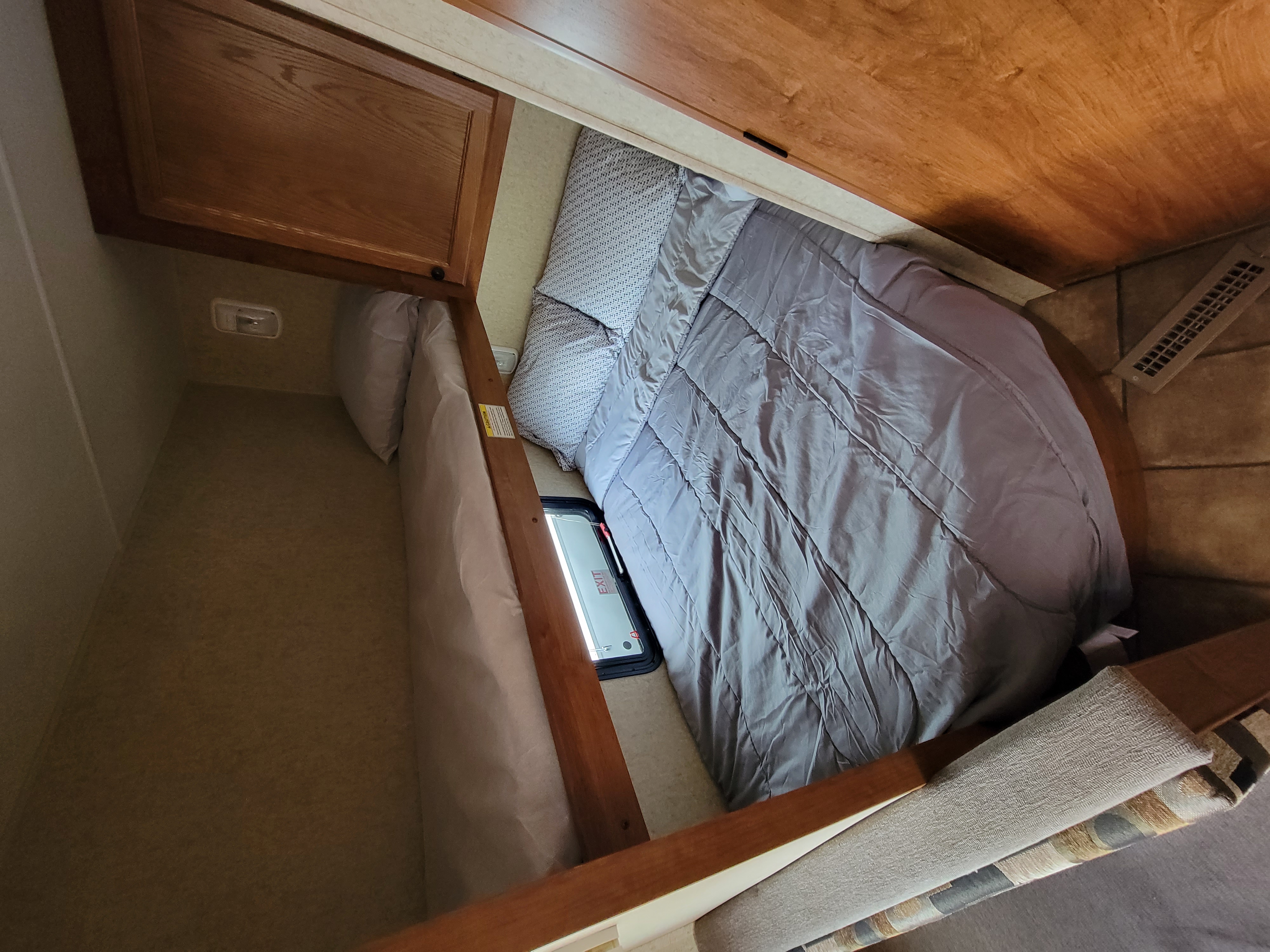 Cozy RV rental bedroom featuring a lower bed with grey bedding and an upper bunk, ideal for comfortable travel.. Heartland RVs Trail Runner 2013