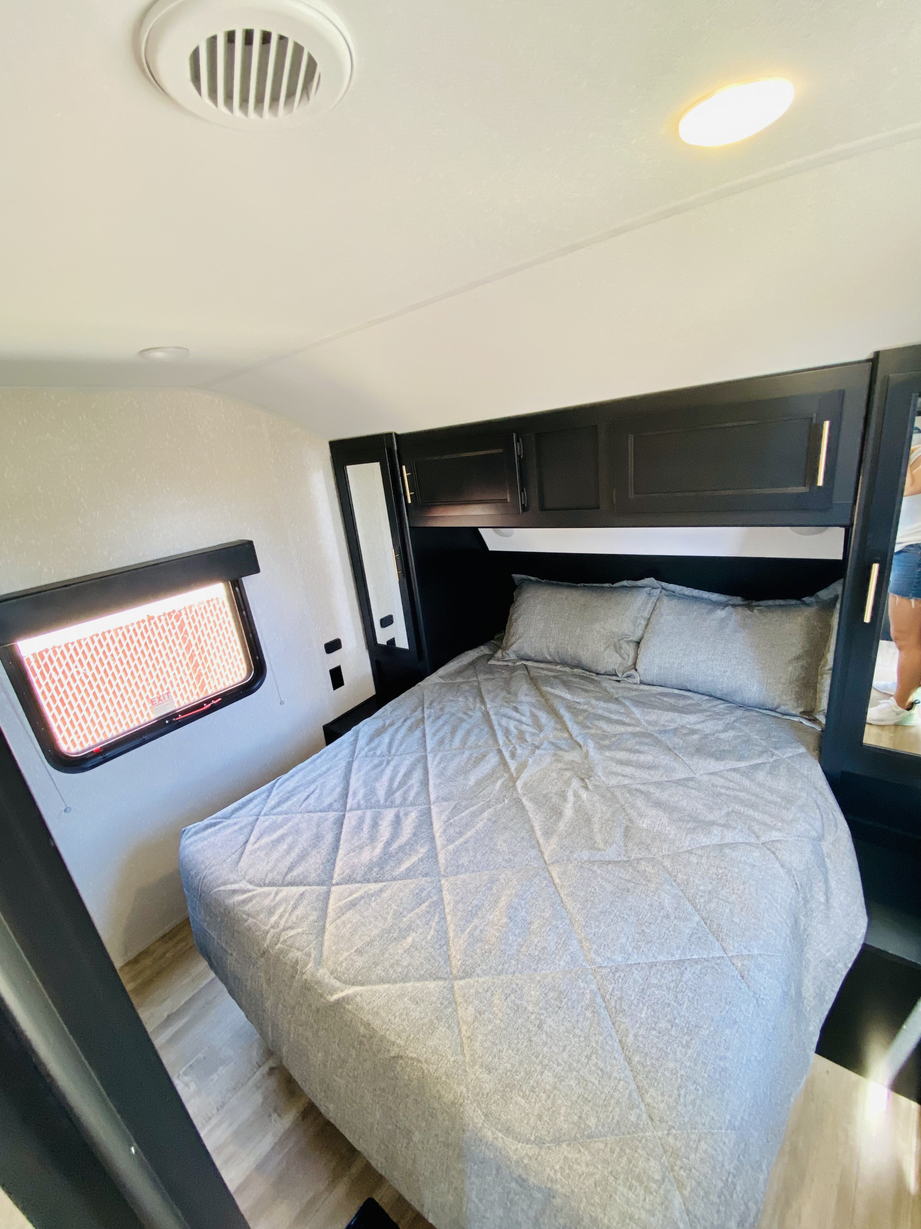 Comfortable RV rental bedroom with grey bedding, overhead storage, and a side window for natural light.. Forest River Cherokee 2022